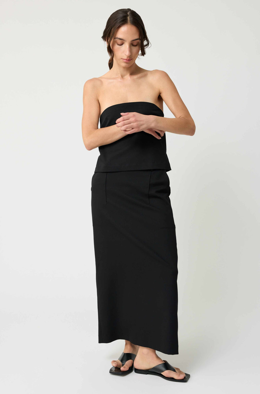 Woman wearing a black strapless top and skirt on a white background