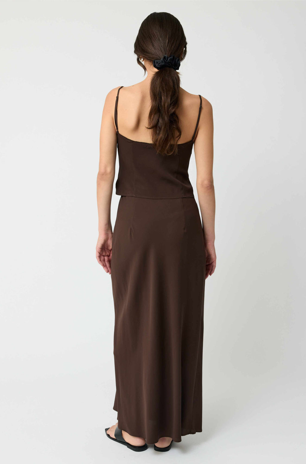 Woman wearing a brown dress from behind on a white background