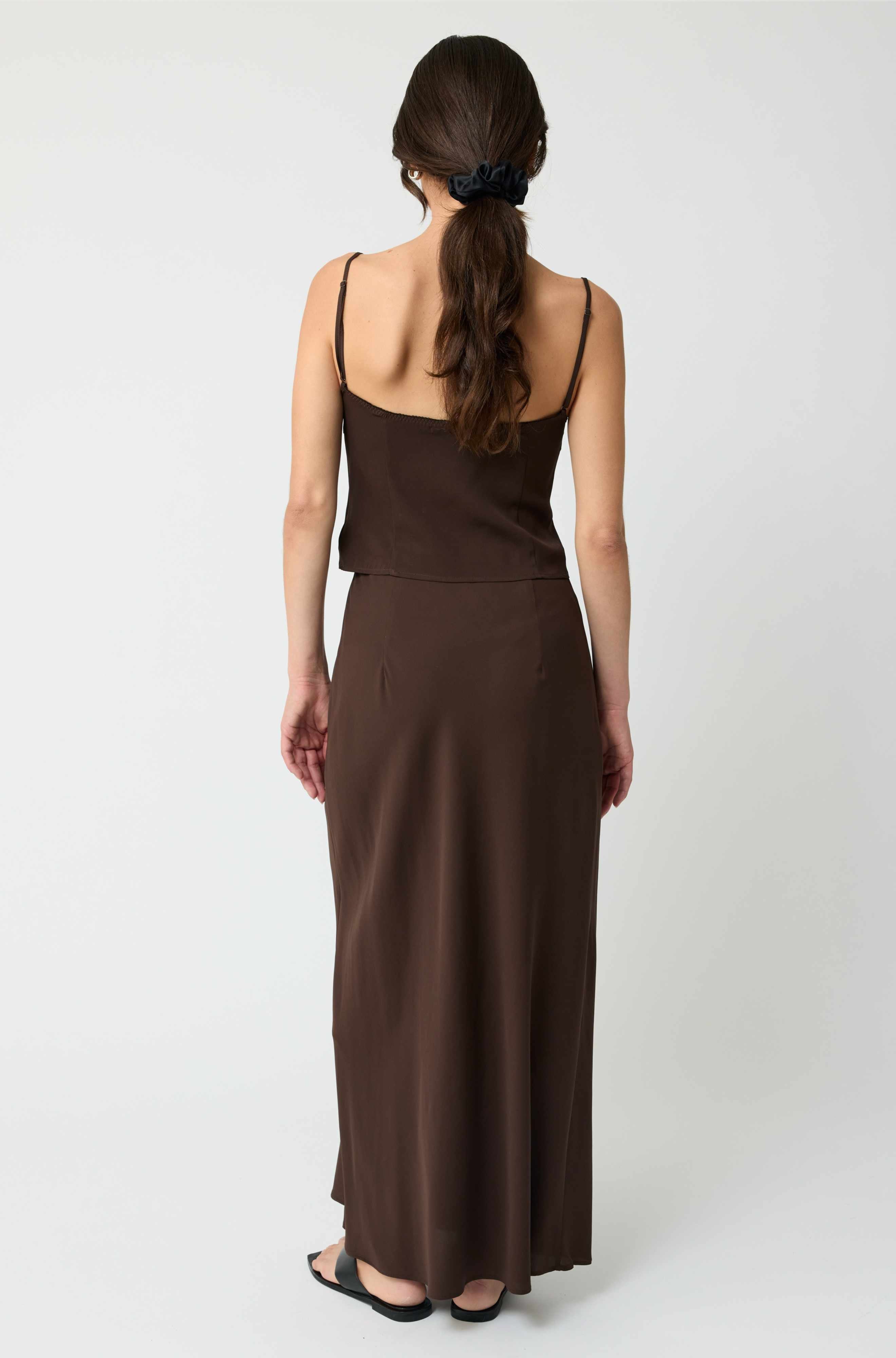 Woman wearing a brown dress from behind on a white background