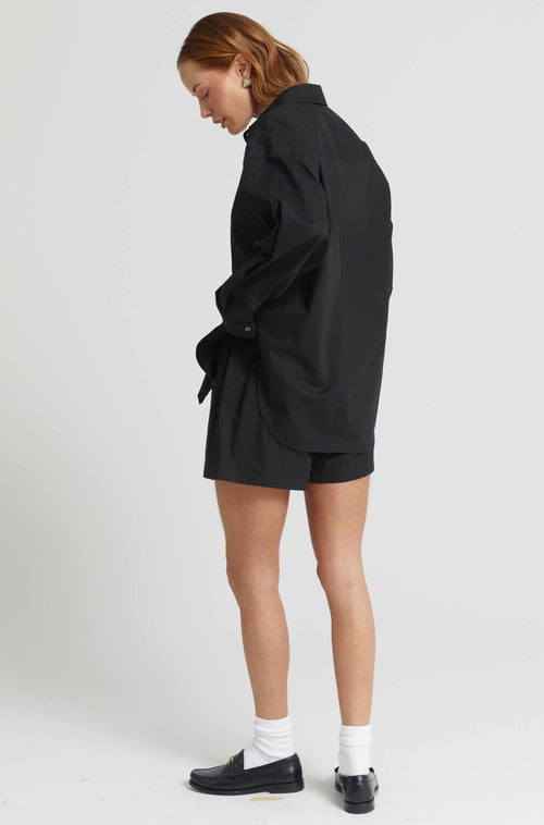 Person wearing a black outfit with shorts on a white background