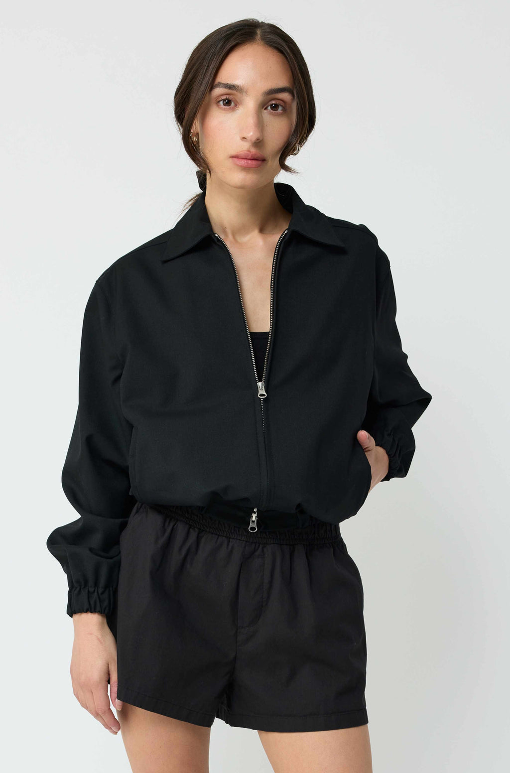 Woman wearing a black jacket and shorts on a white background