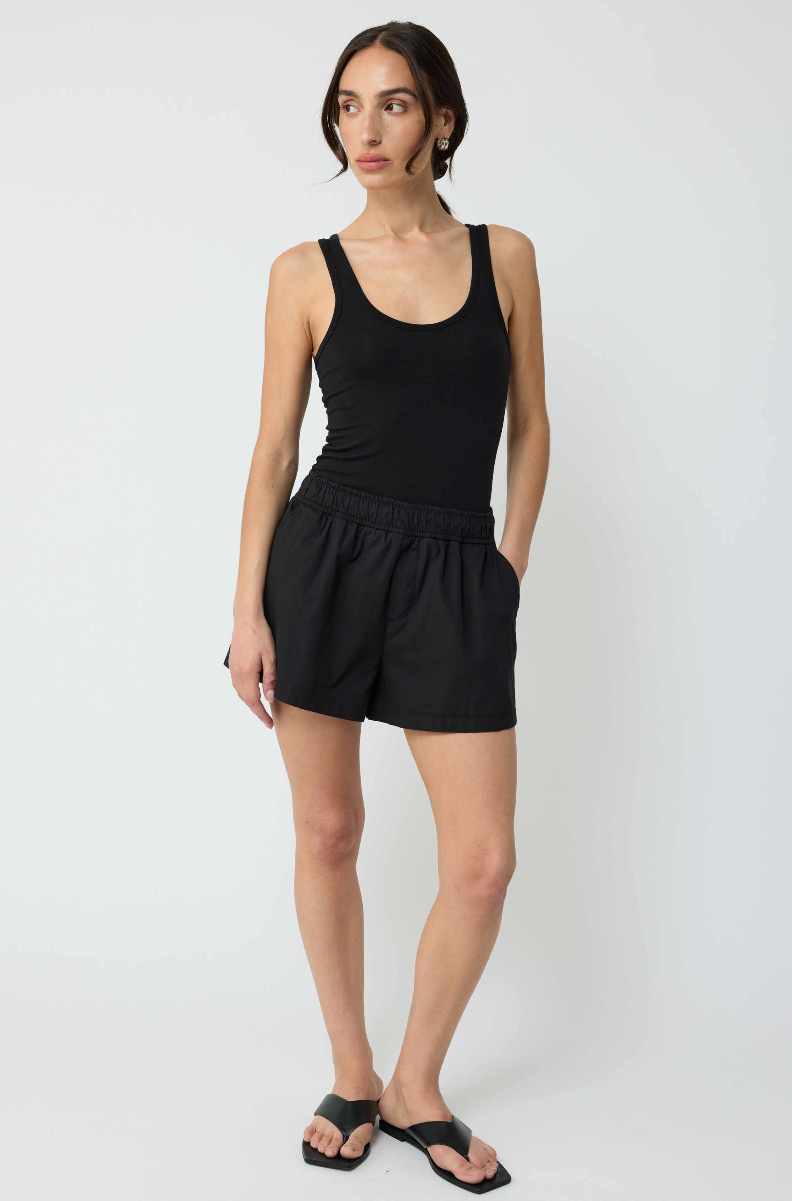 Woman wearing a black tank top and black shorts on a white background