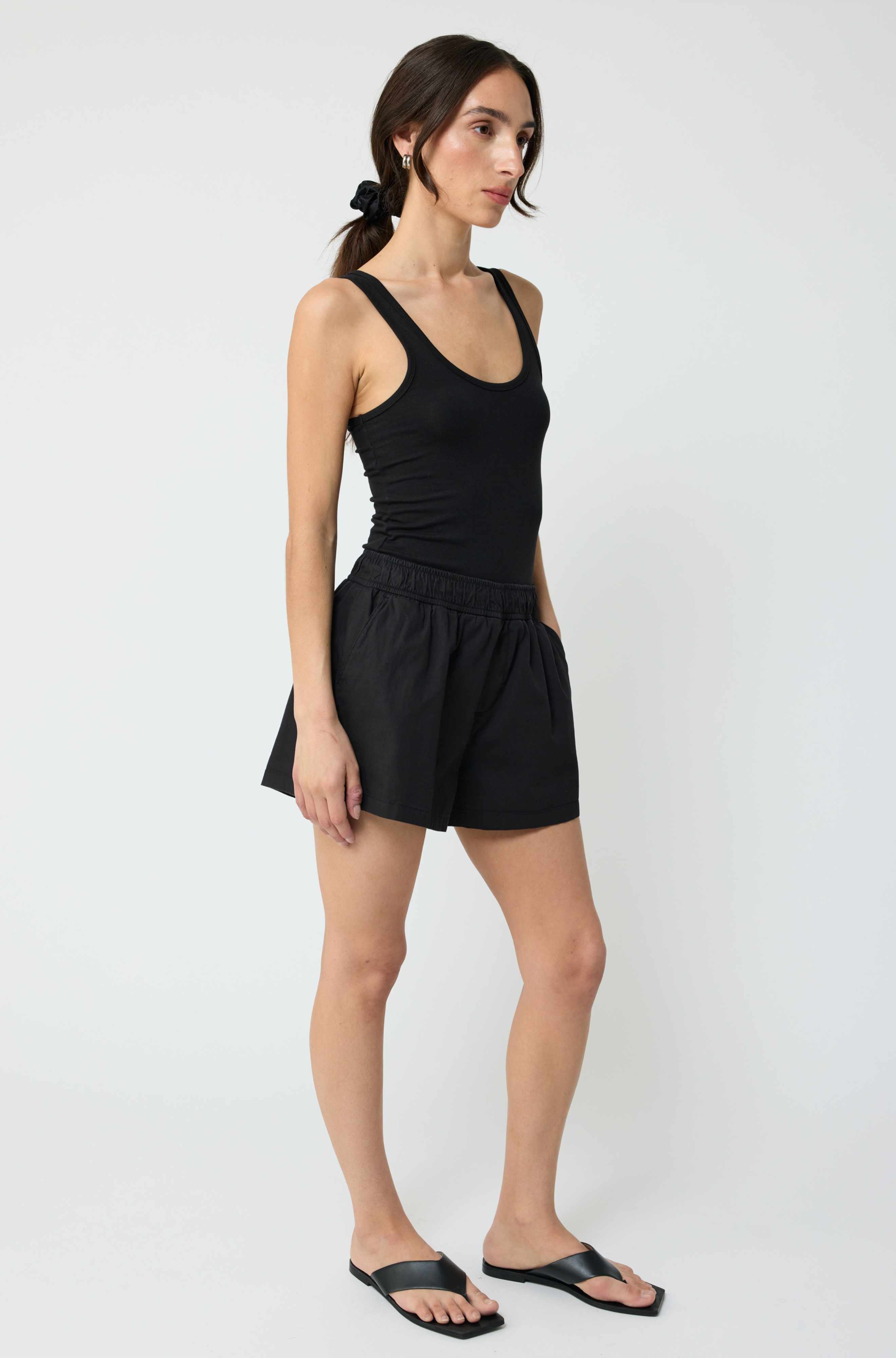 Woman wearing a black tank top and black shorts on a white background