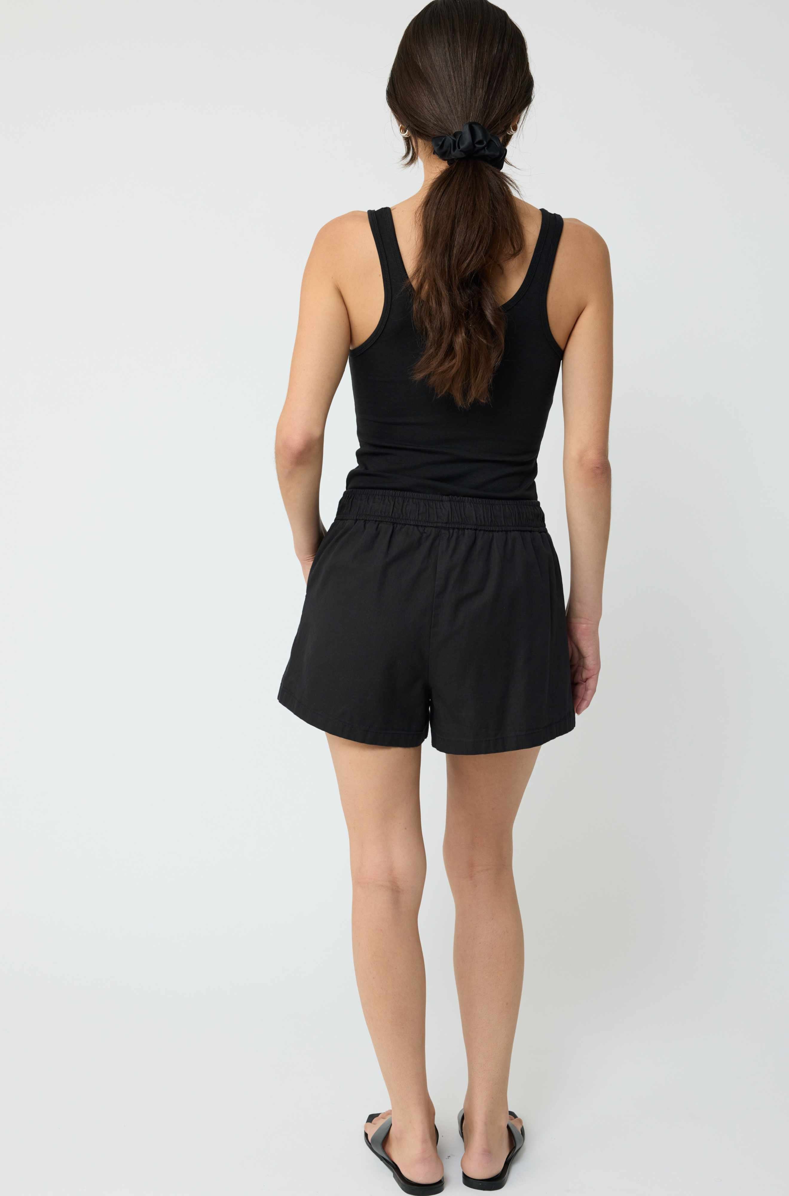 Person wearing a black tank top and shorts on a white background