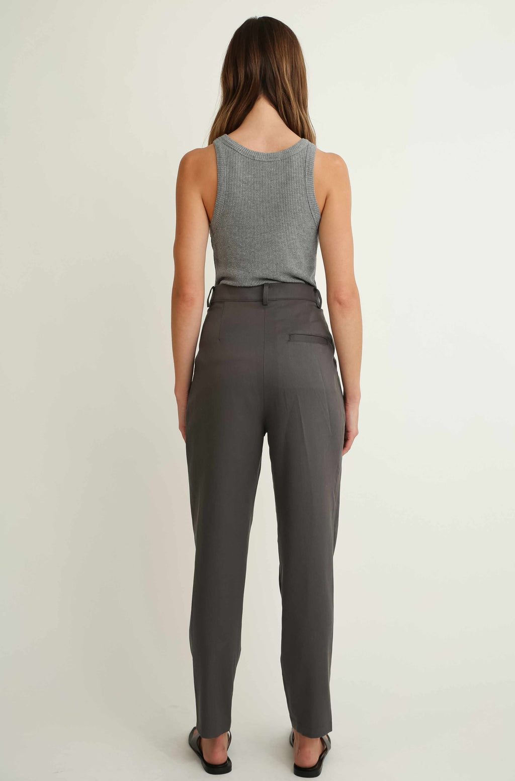 Woman wearing a gray sleeveless top and gray pants on a white background