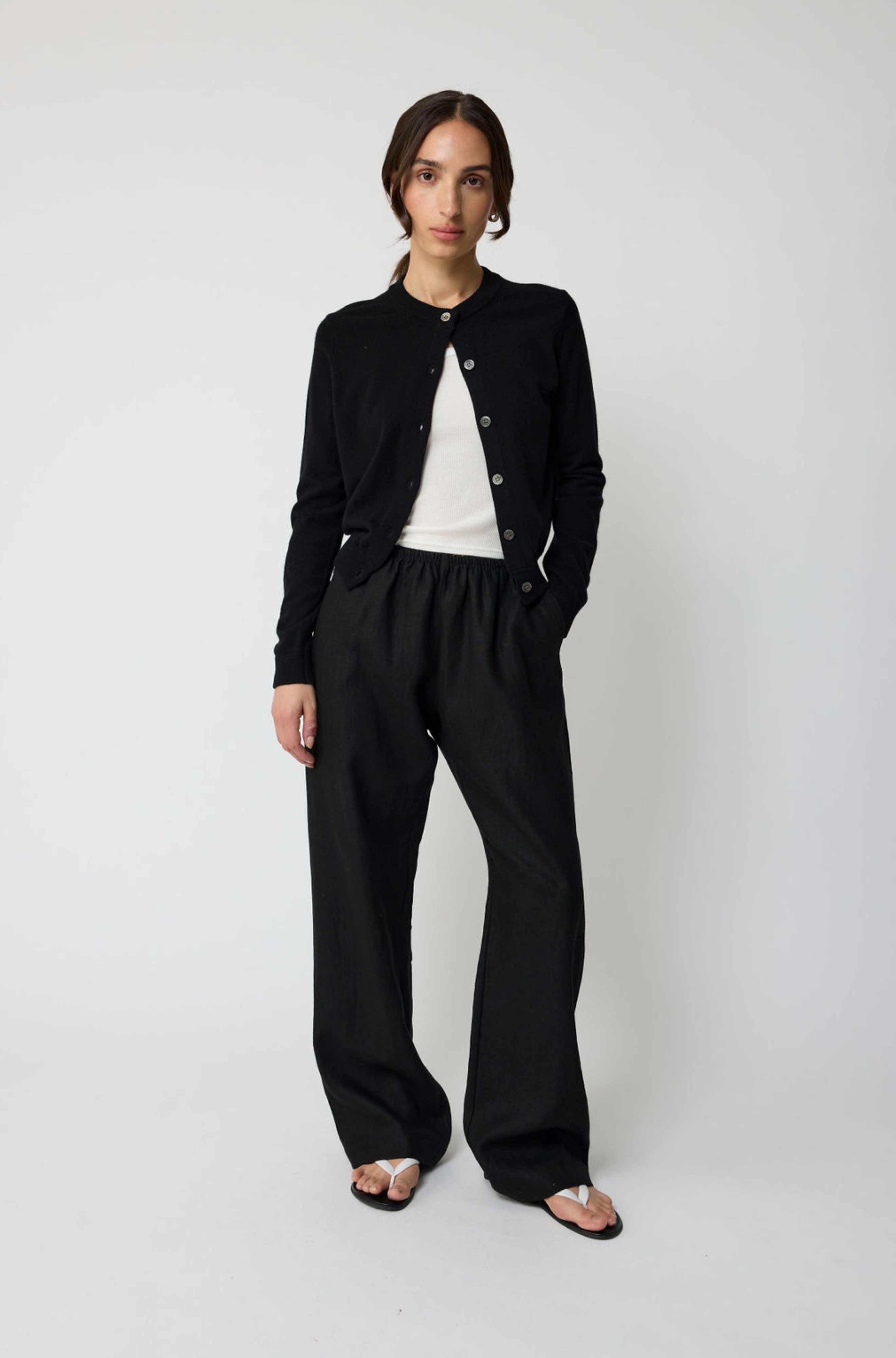 Person wearing a black cardigan and pants on a white background