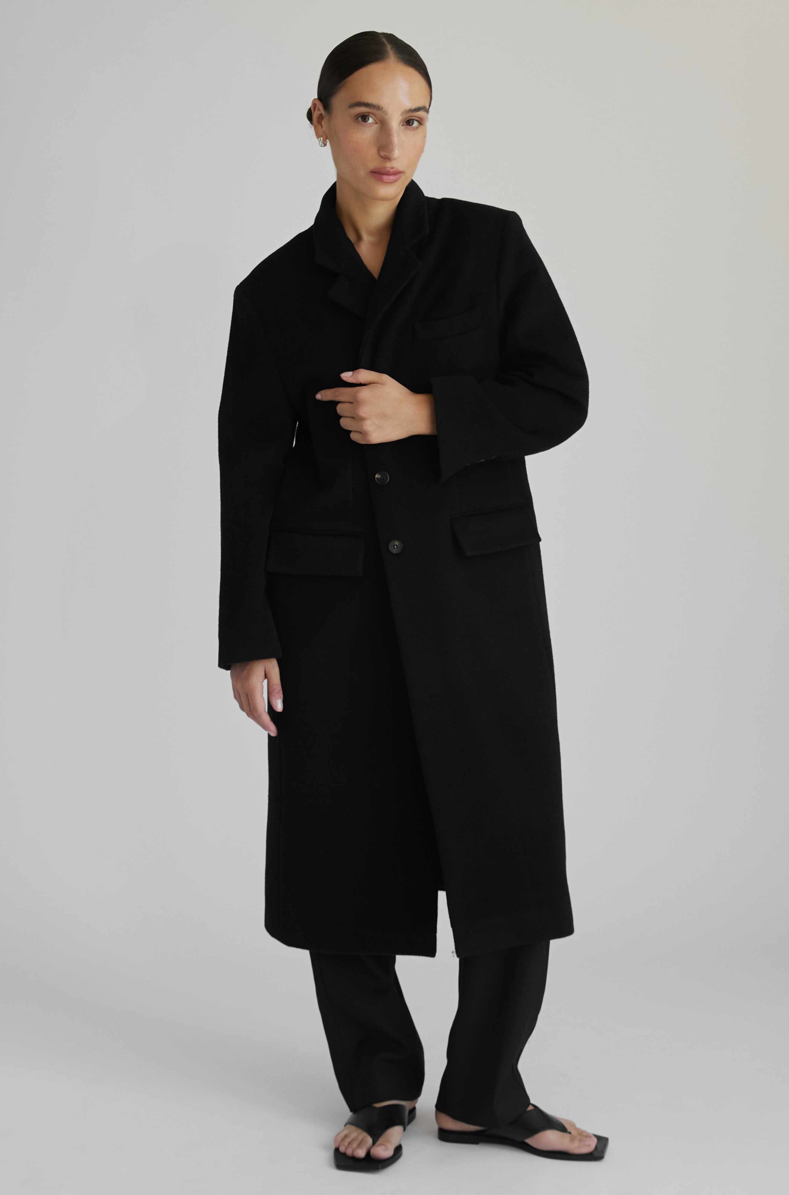 Person wearing a black coat on a plain background