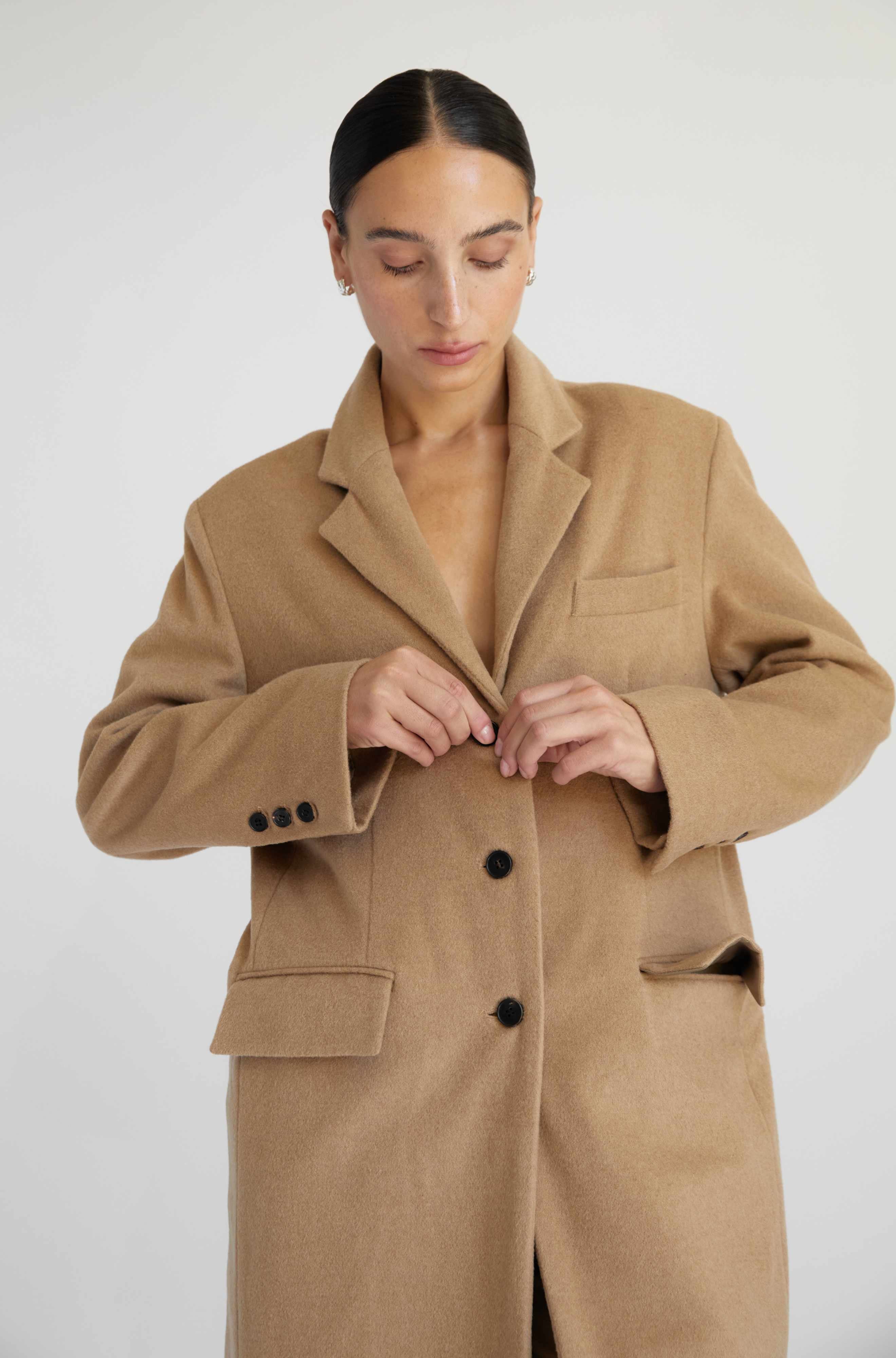 Woman wearing a beige coat against a white background