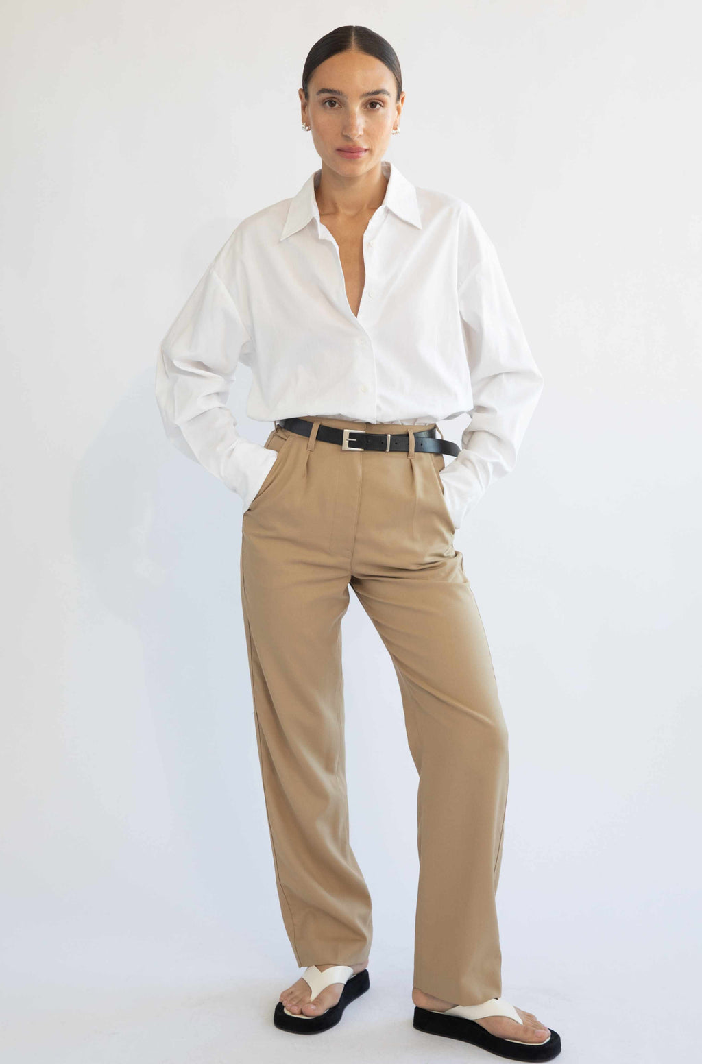 Woman wearing beige trousers with a tucked in white shirt