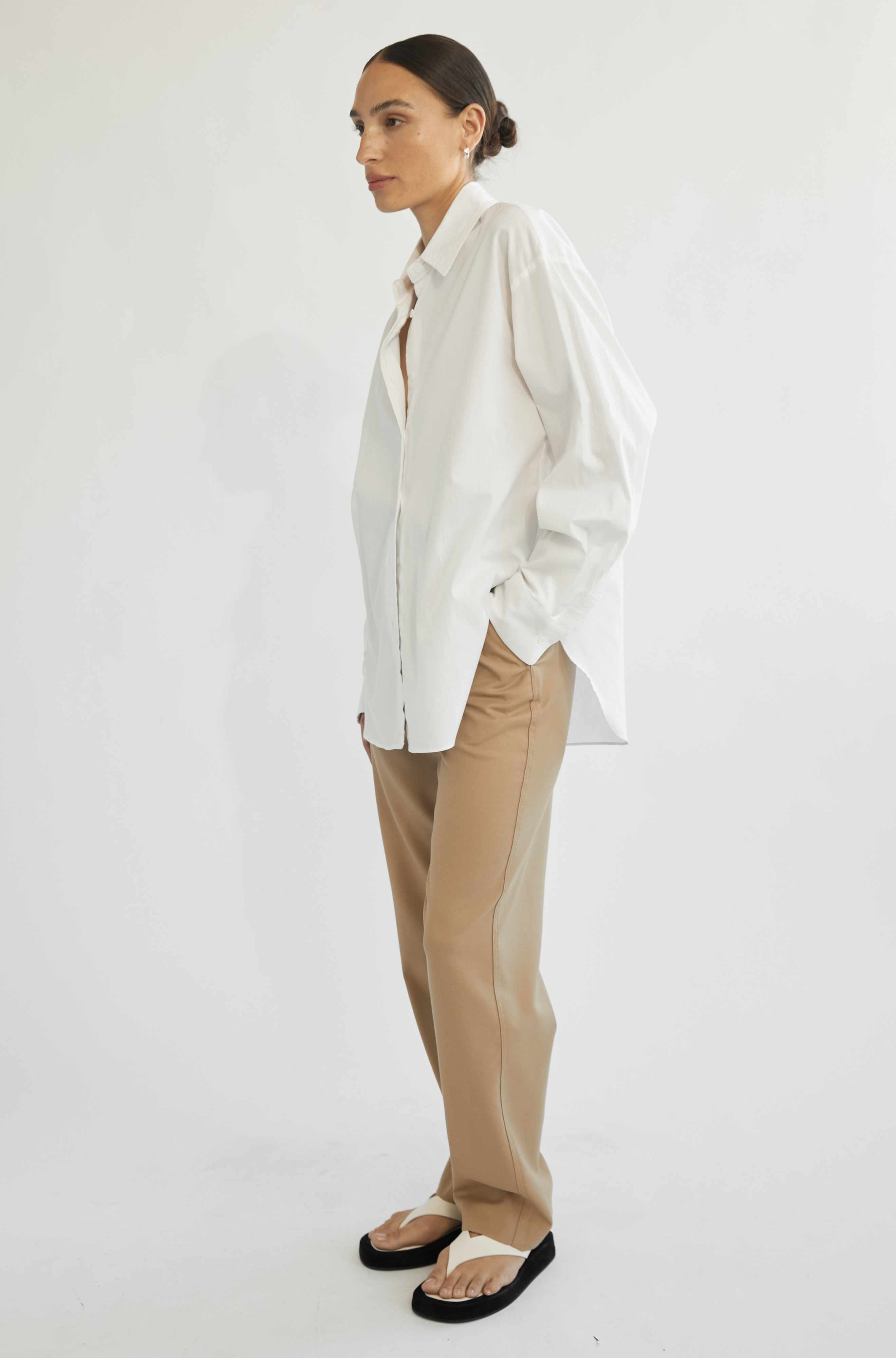 Woman wearing a white shirt and beige pants on a white background