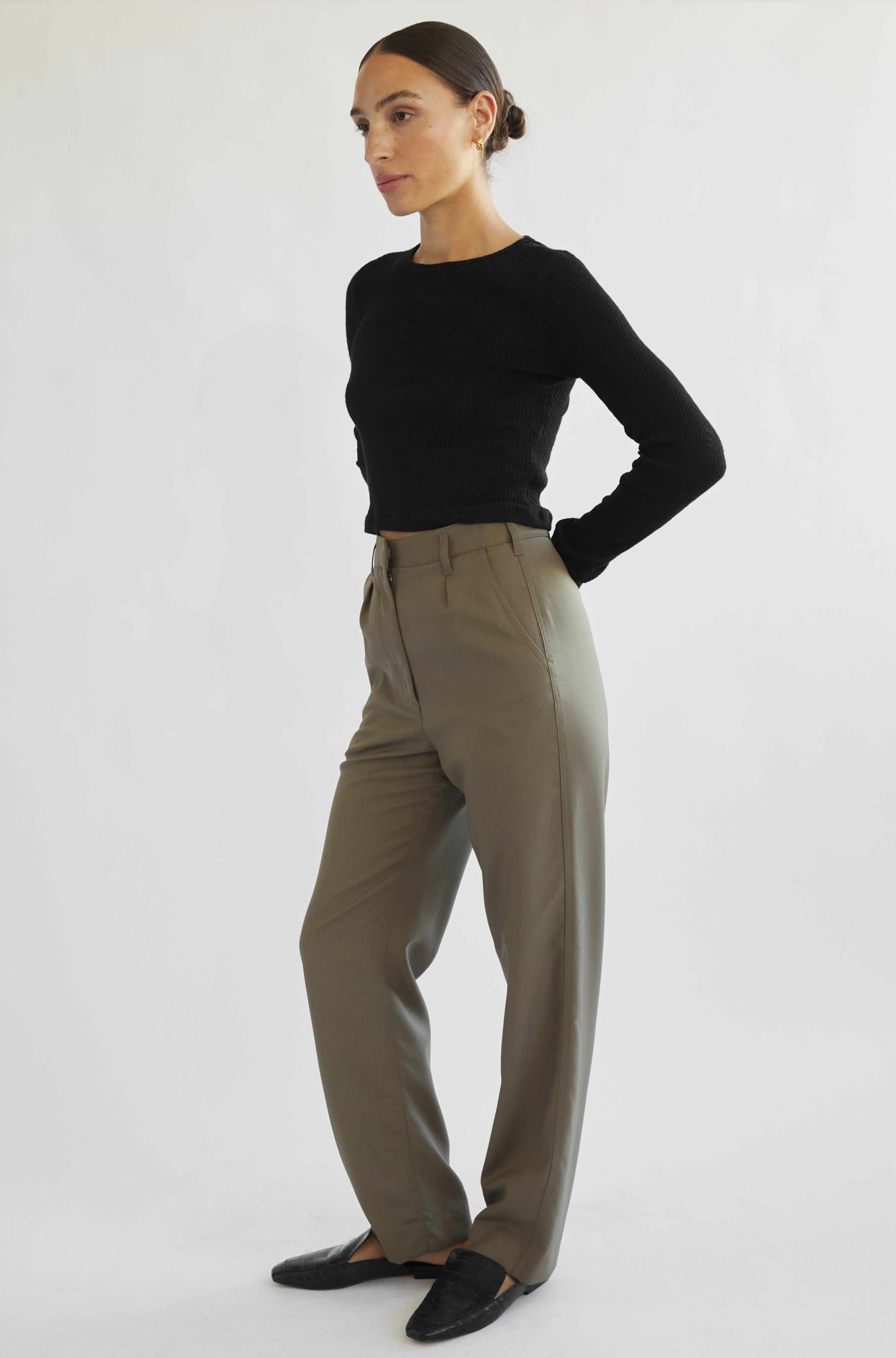 Woman wearing a black top and beige pants on a white background