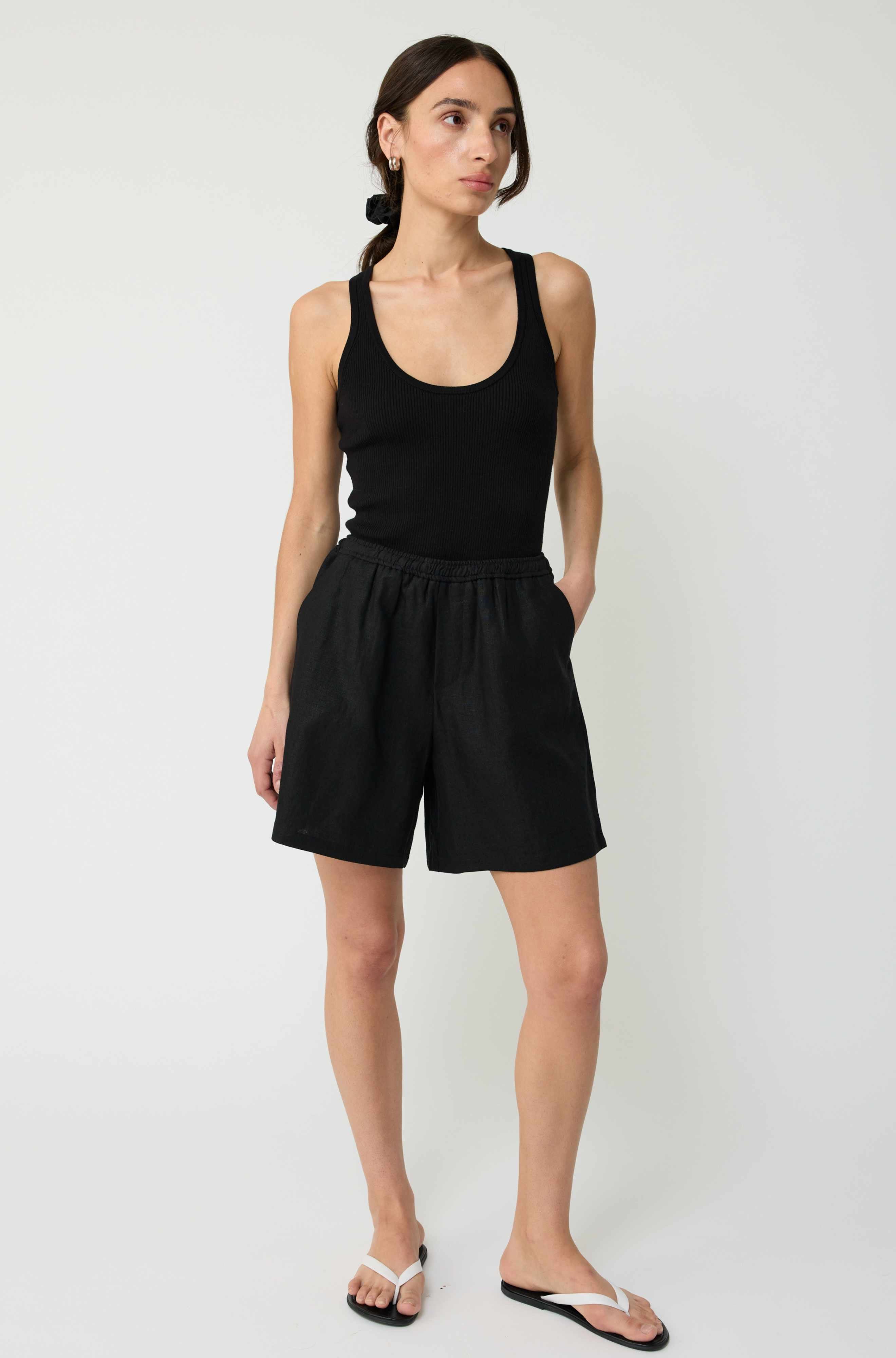 Woman wearing a black tank top and black shorts on a white background