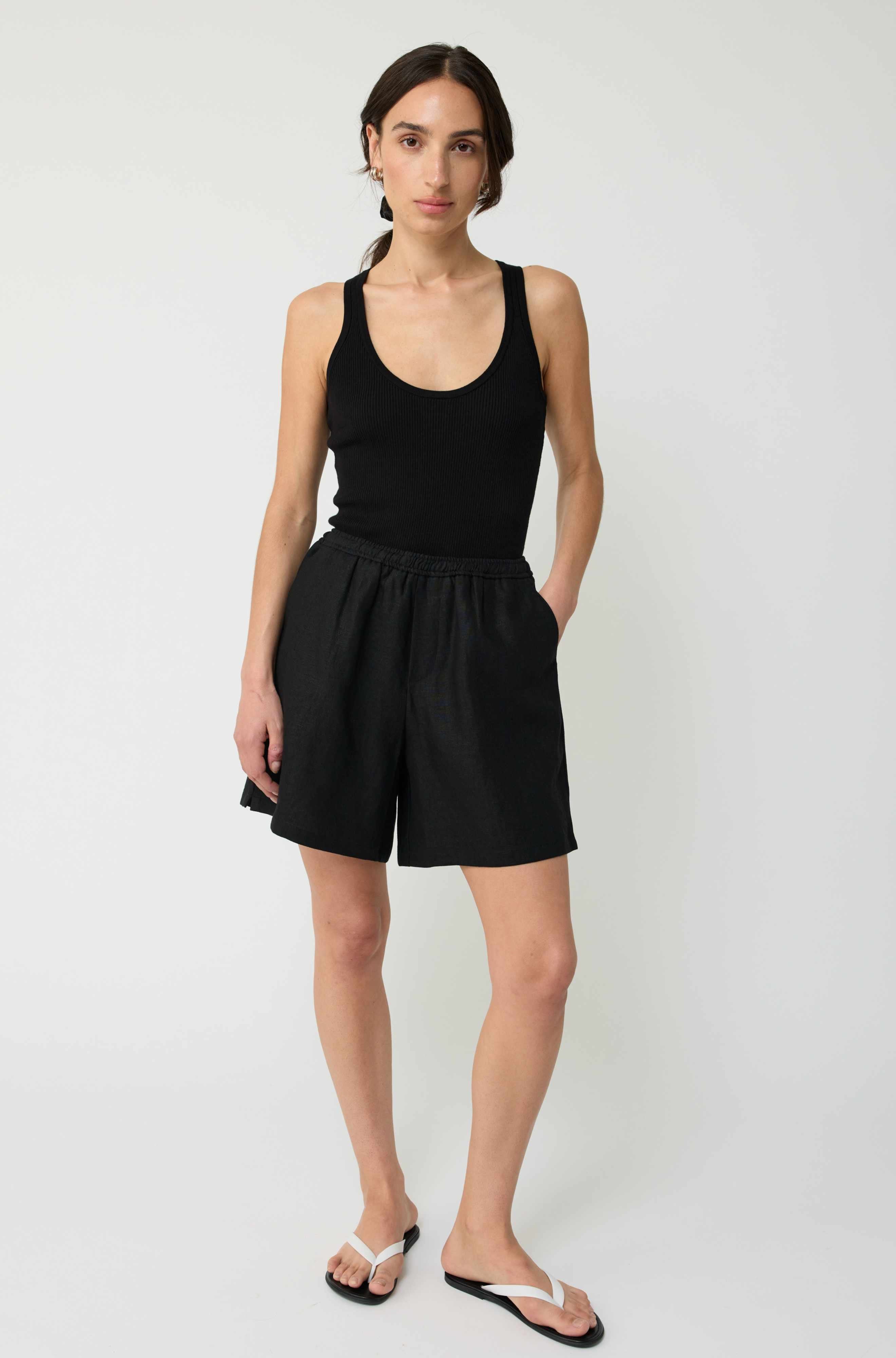 Woman wearing a black tank top and shorts on a white background