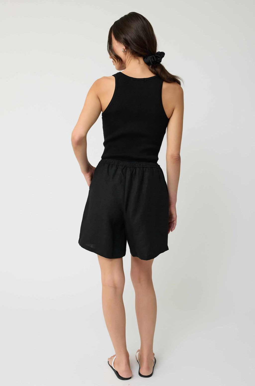 Woman wearing a black sleeveless top and shorts on a white background