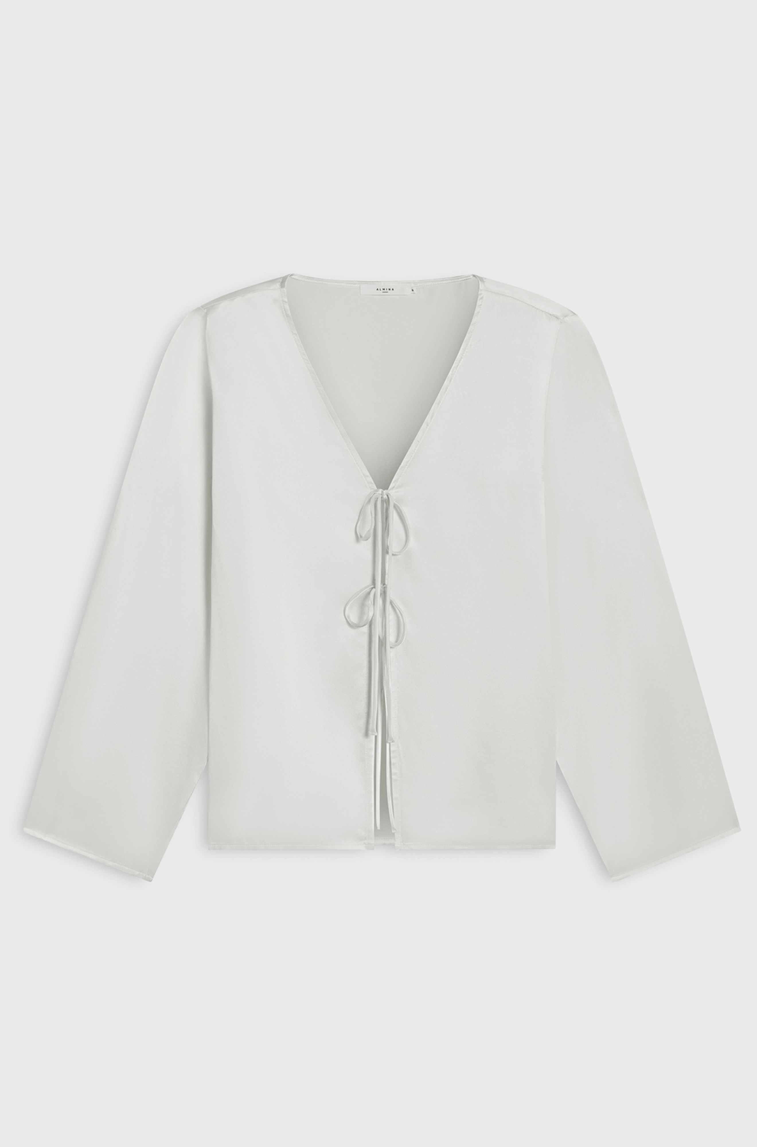 White blouse with a V-neck and long sleeves on a light gray background