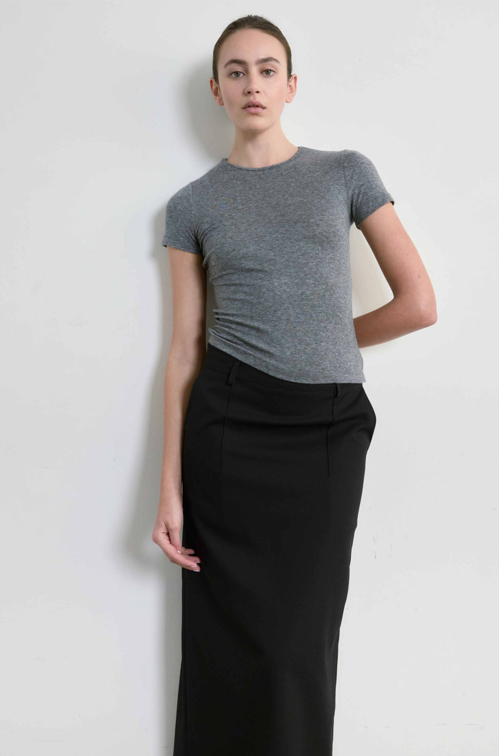 Person wearing a gray t-shirt and black pants against a white background