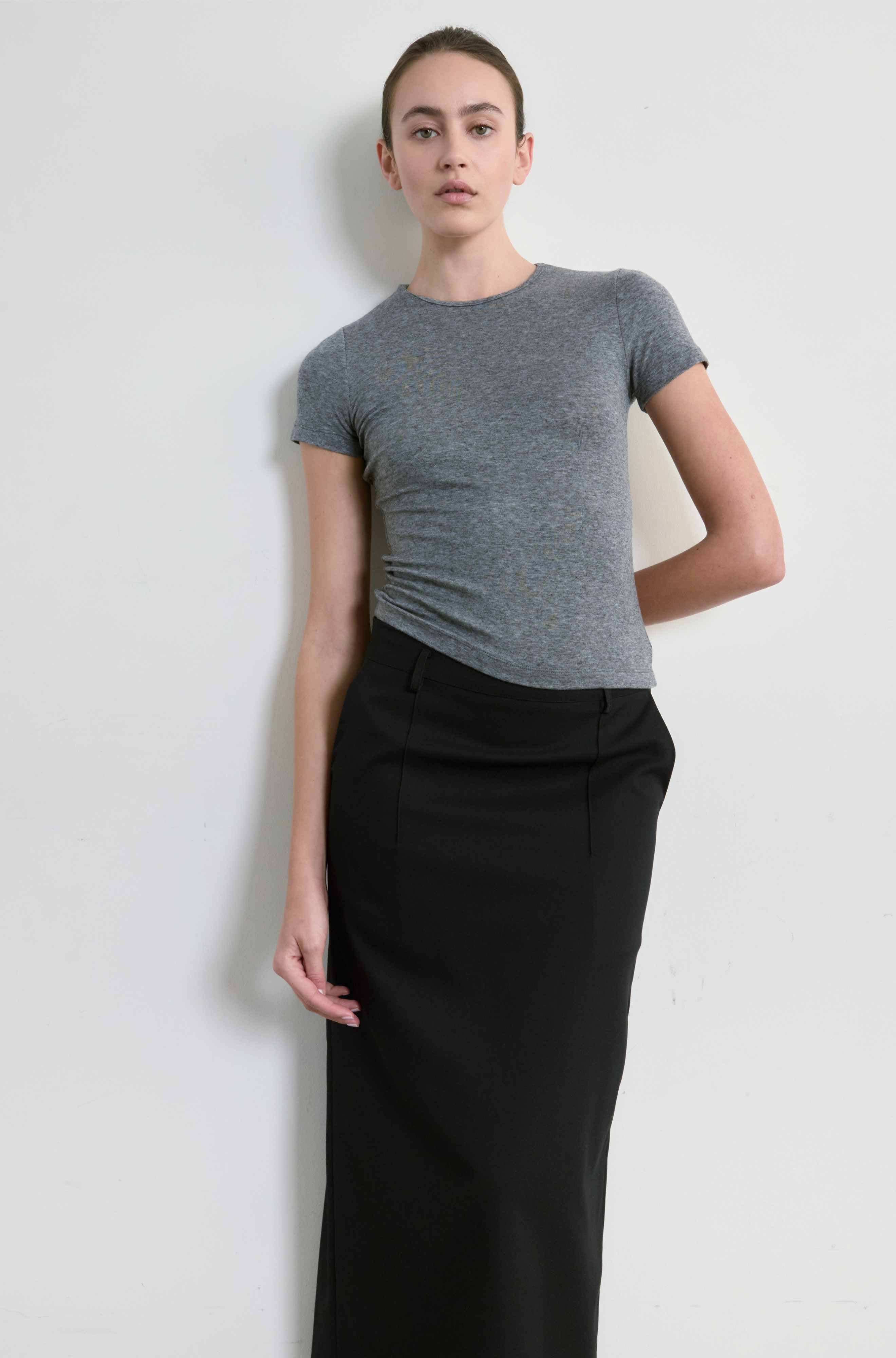 Person wearing a gray t-shirt and black pants against a white background