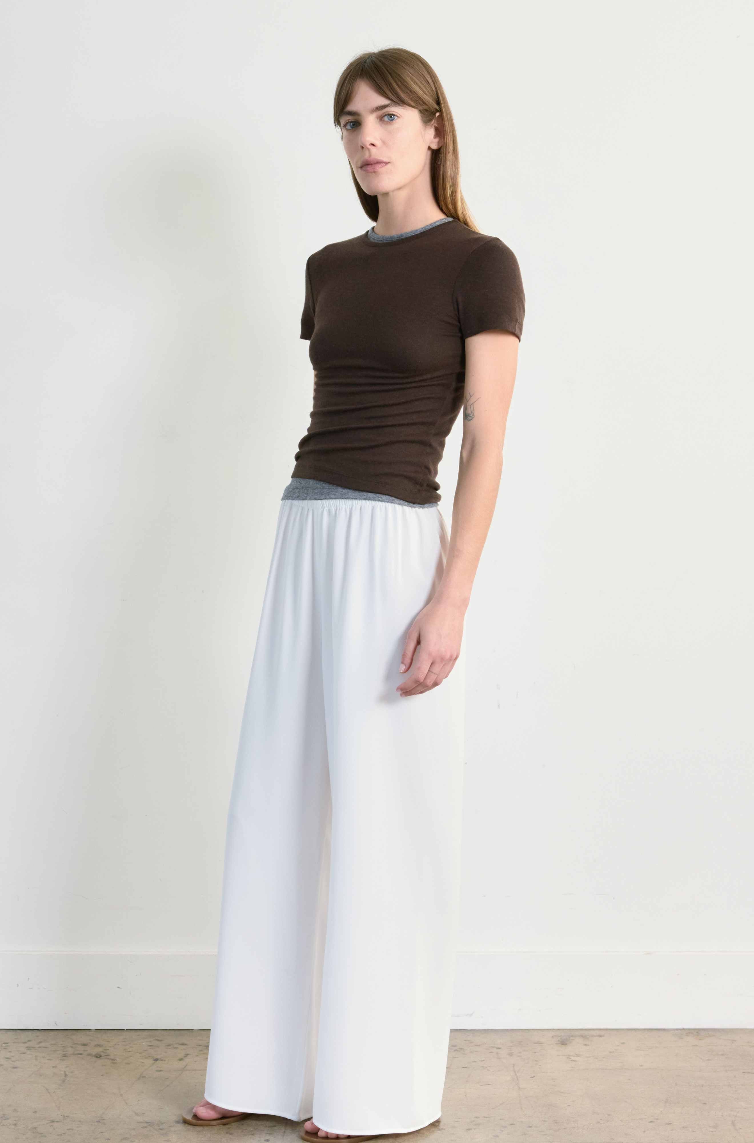 Woman wearing a brown top and white skirt against a plain background