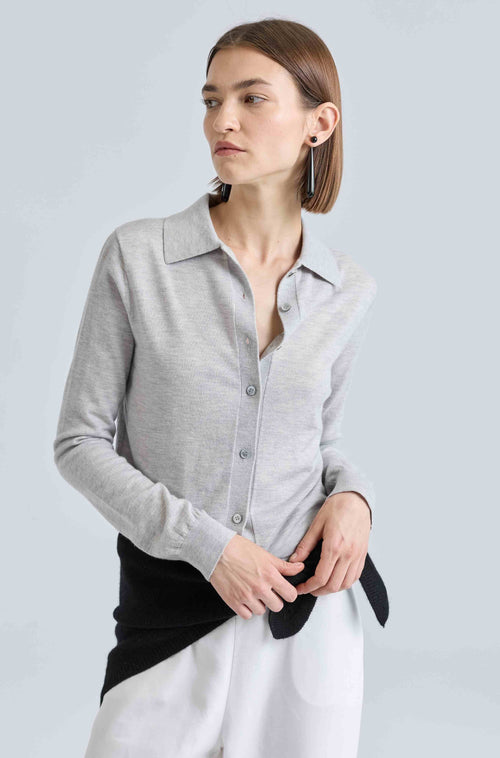 Woman wearing a gray cardigan over a white shirt on a light gray background