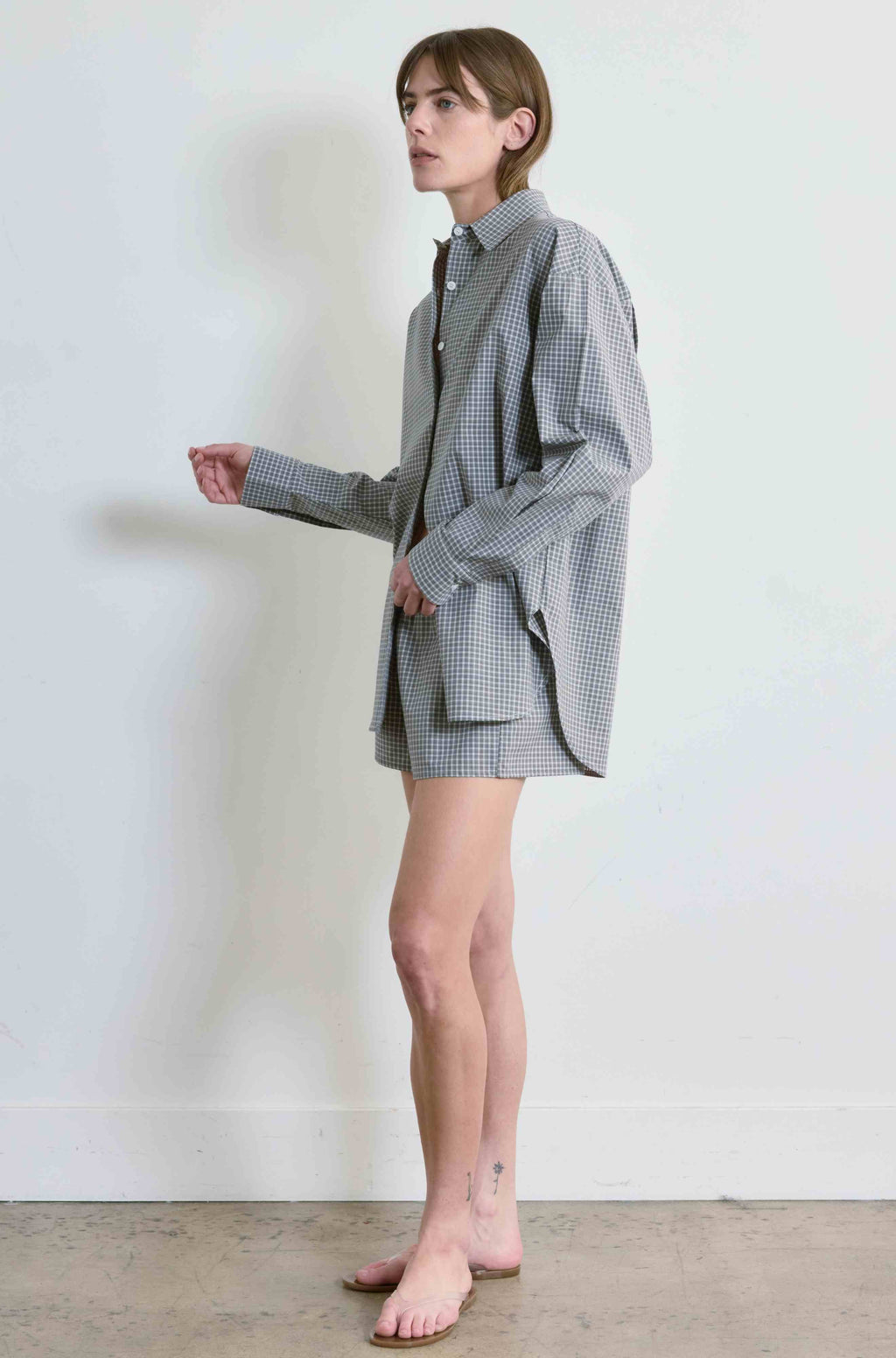 Person wearing a gray checkered outfit against a white background