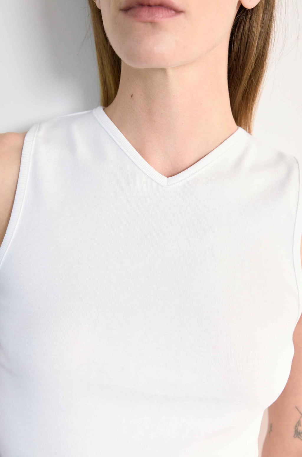 White sleeveless top worn by a person on a white background