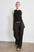 Person wearing a black sleeveless top and dark pants against a white background