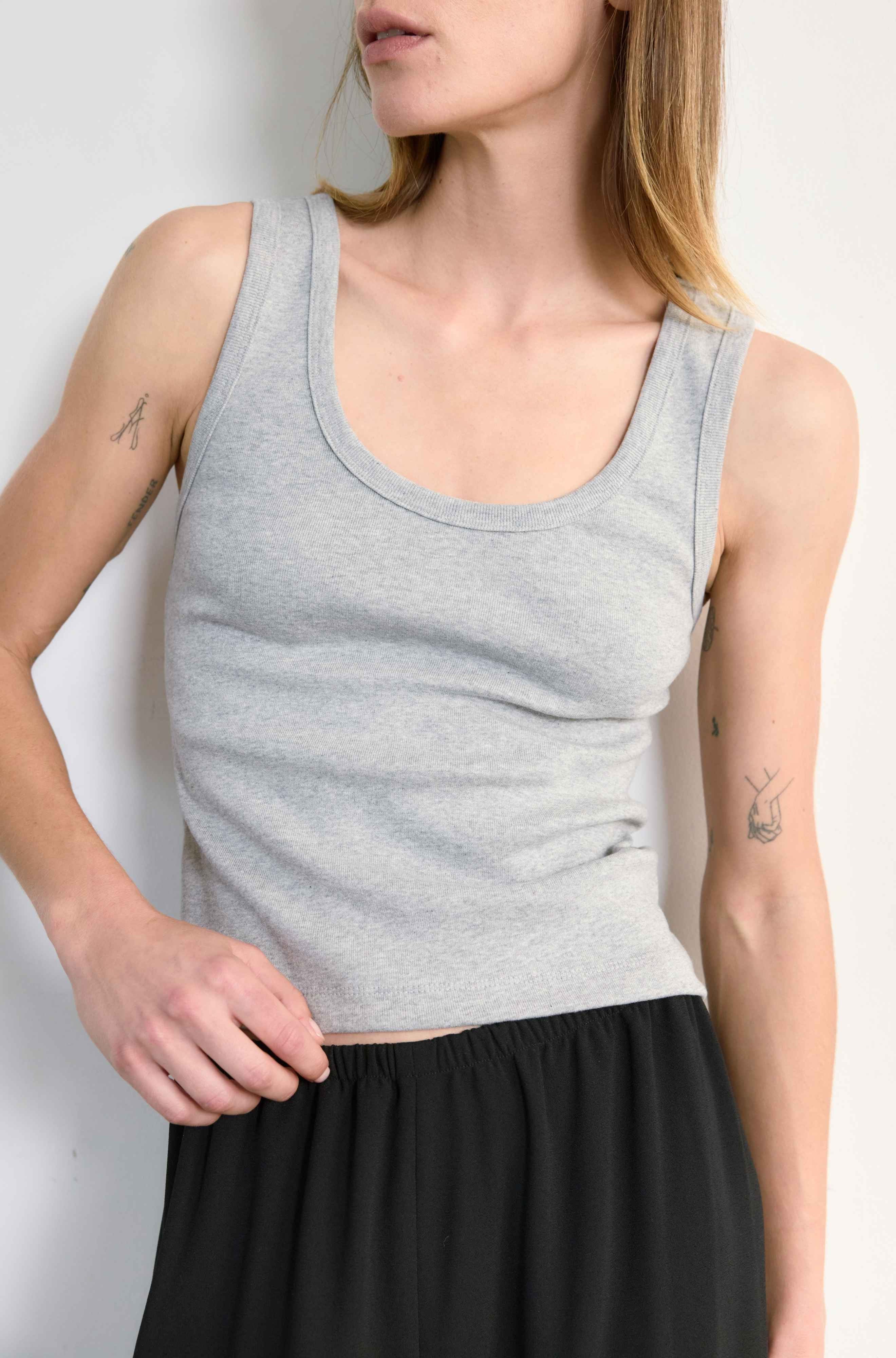 Woman wearing a gray tank top and black skirt against a white background