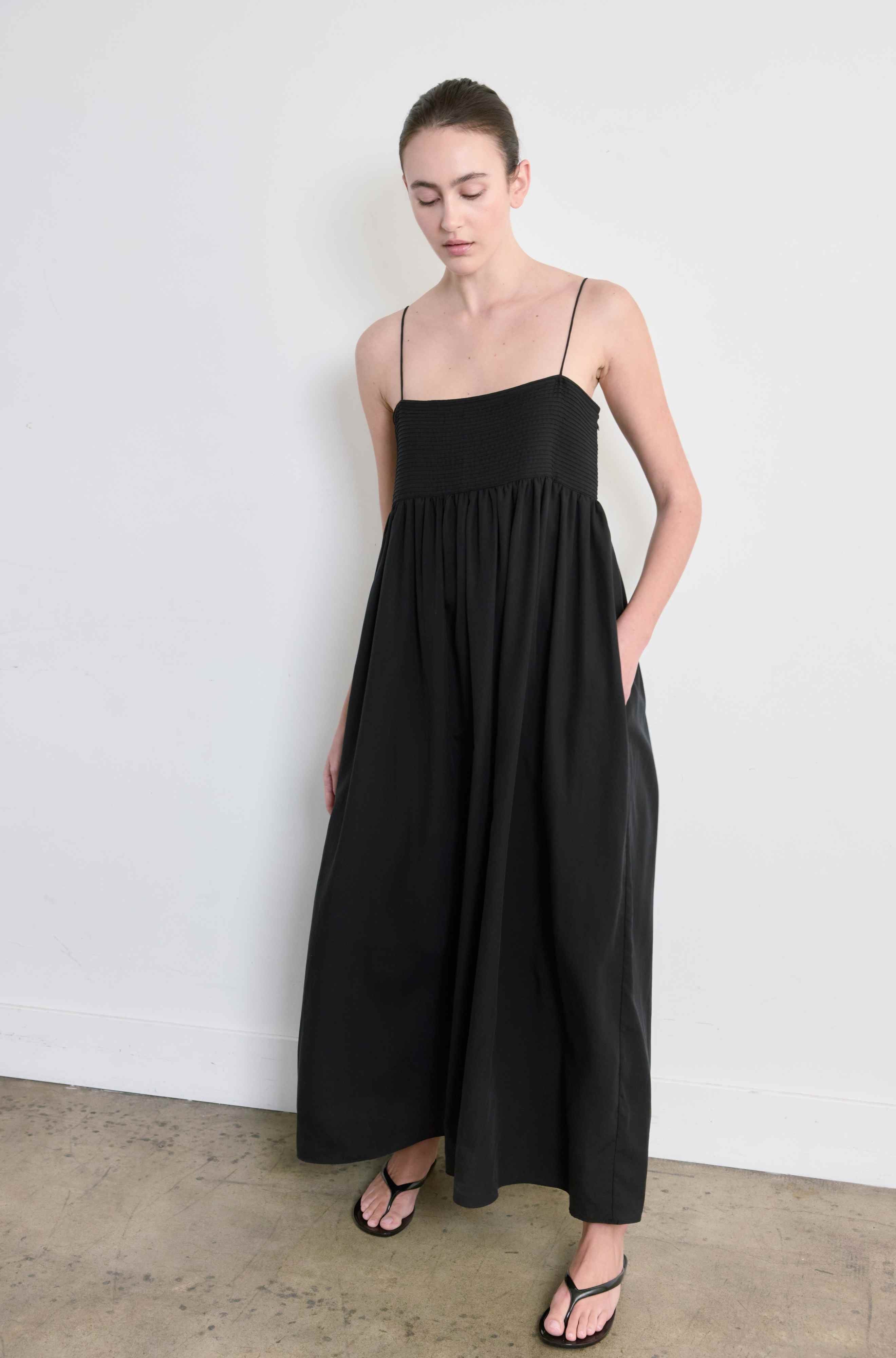 Woman wearing a black dress against a white wall