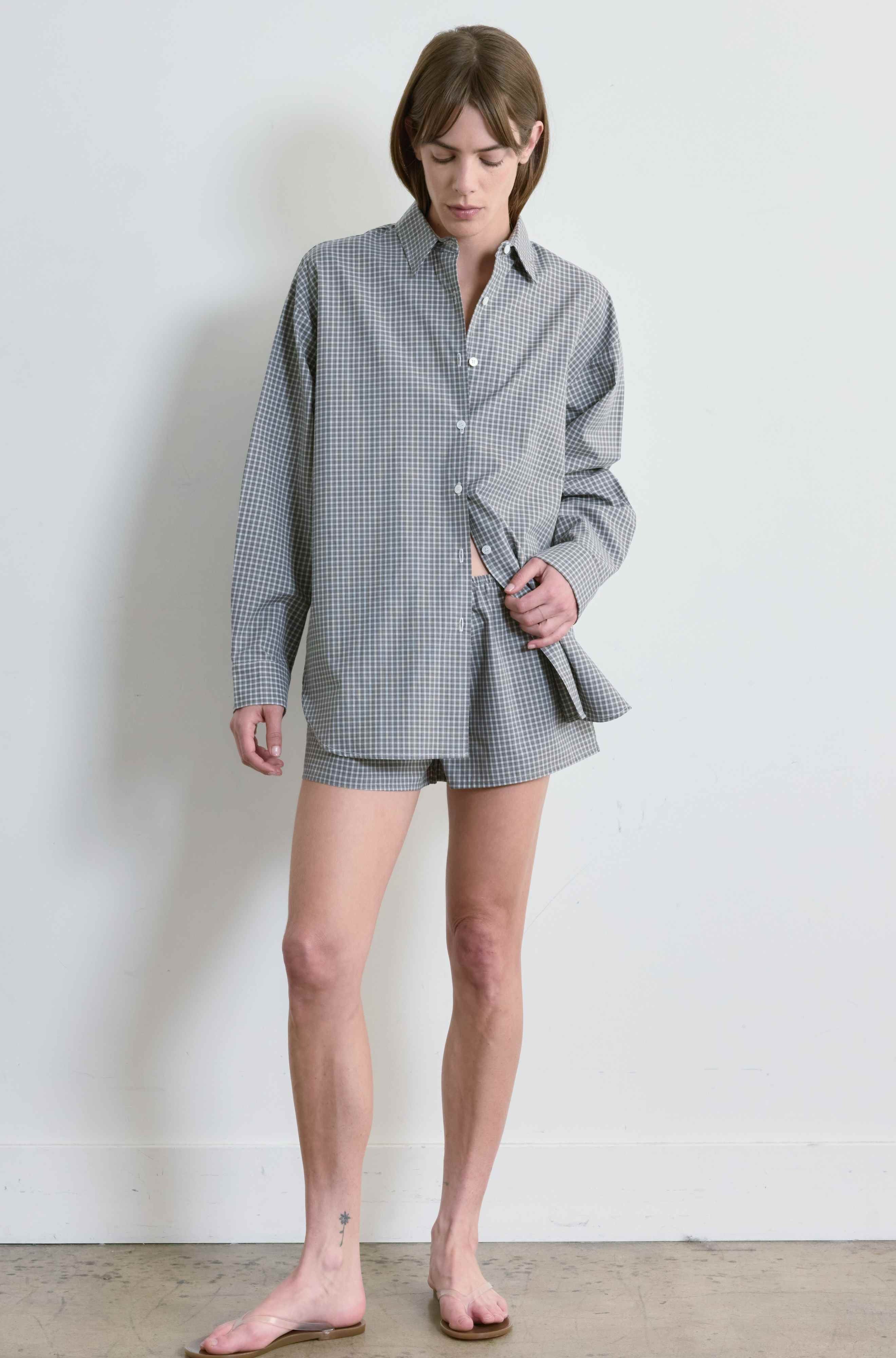 Person wearing a checkered shirt and shorts against a white background