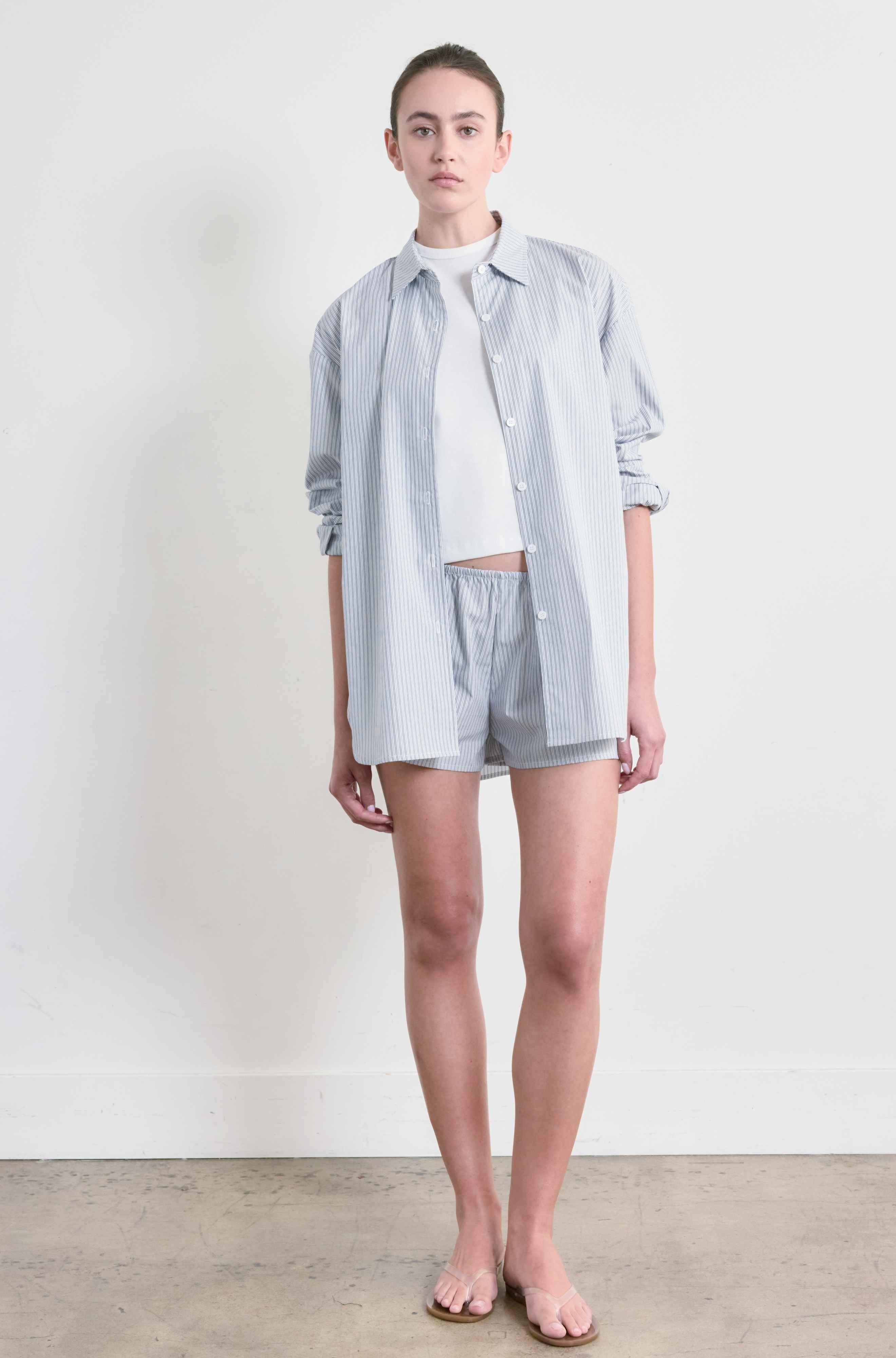 Person wearing a light blue striped shirt and shorts on a white background