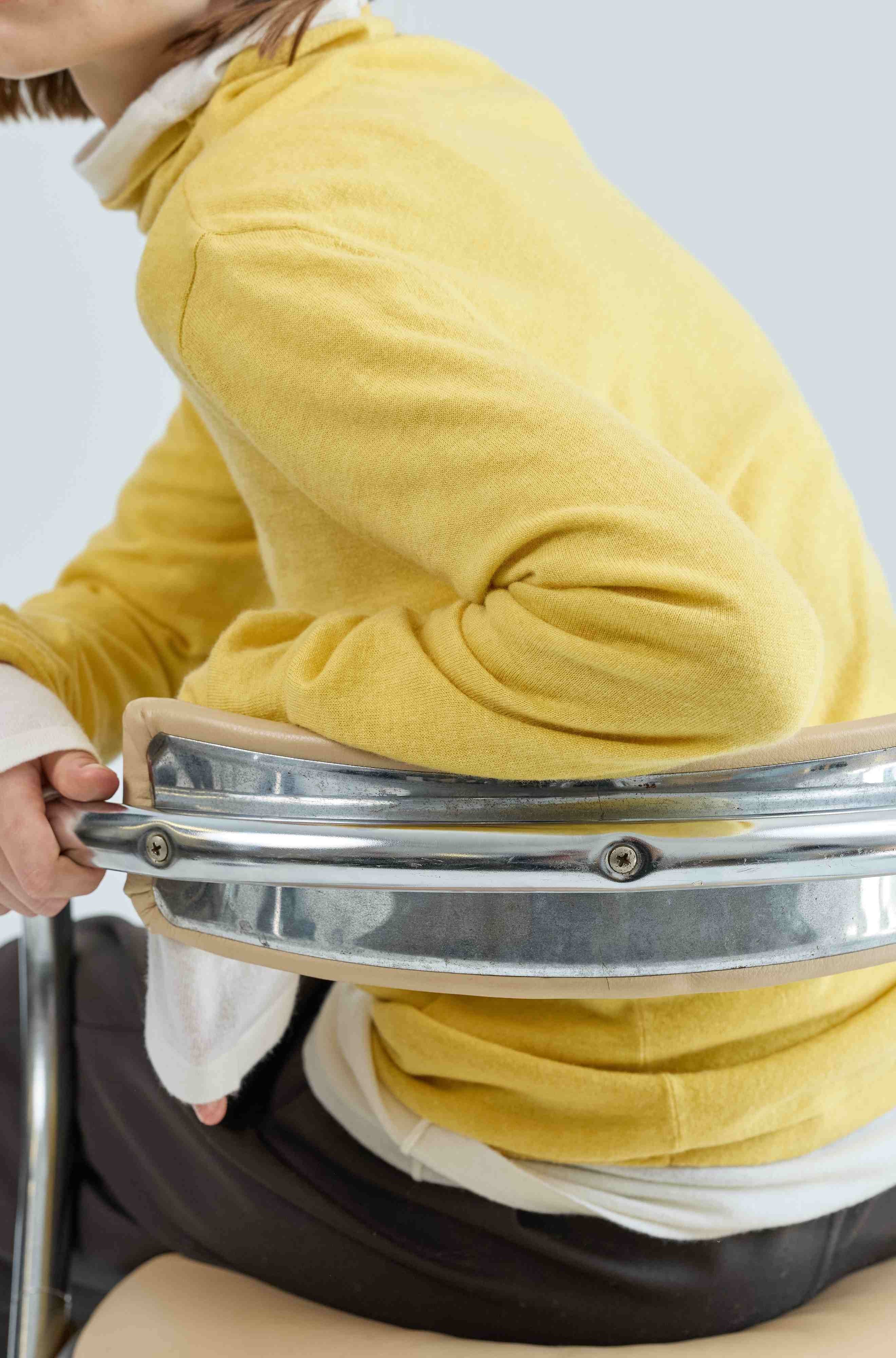 Woman wearing a yellow wool turtleneck over a matching ivory turtleneck with a white background