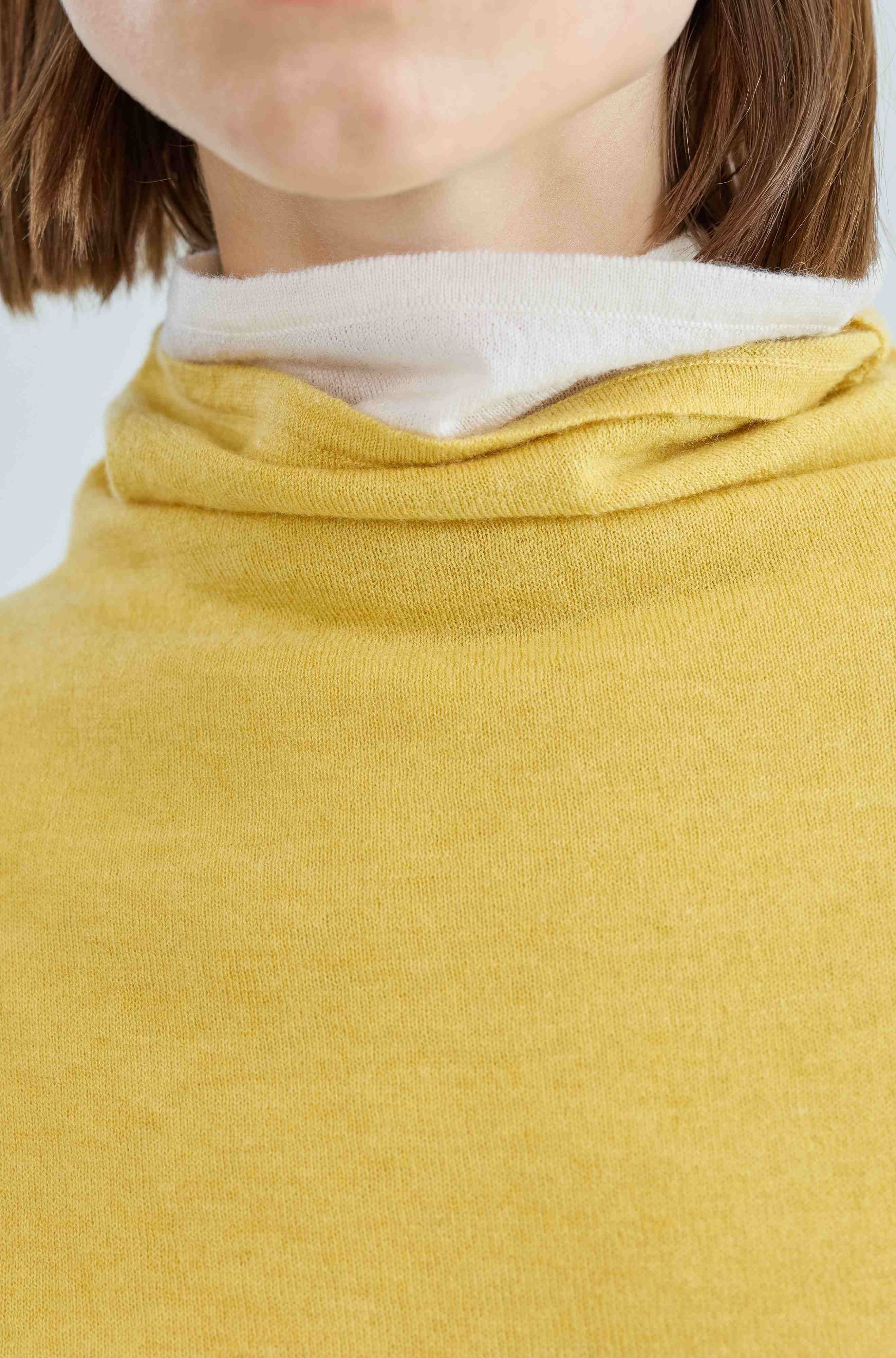 Close-up of a person wearing a mustard yellow garment with a white layered top.