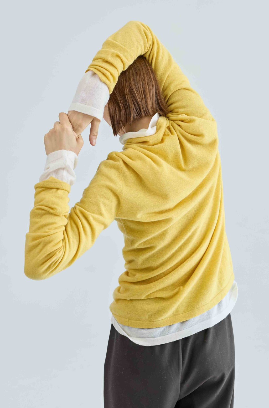 Person wearing a yellow turtleneck over a white turtleneck with a light gray background
