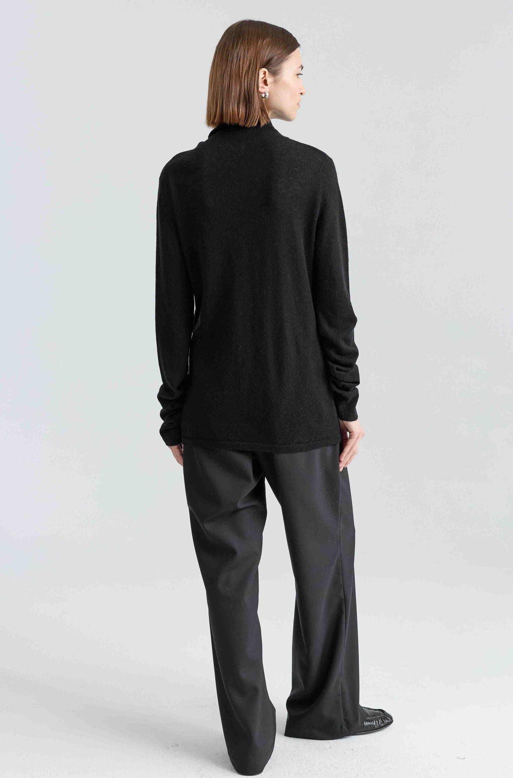 Person wearing a black turtleneck and black pants on a white background