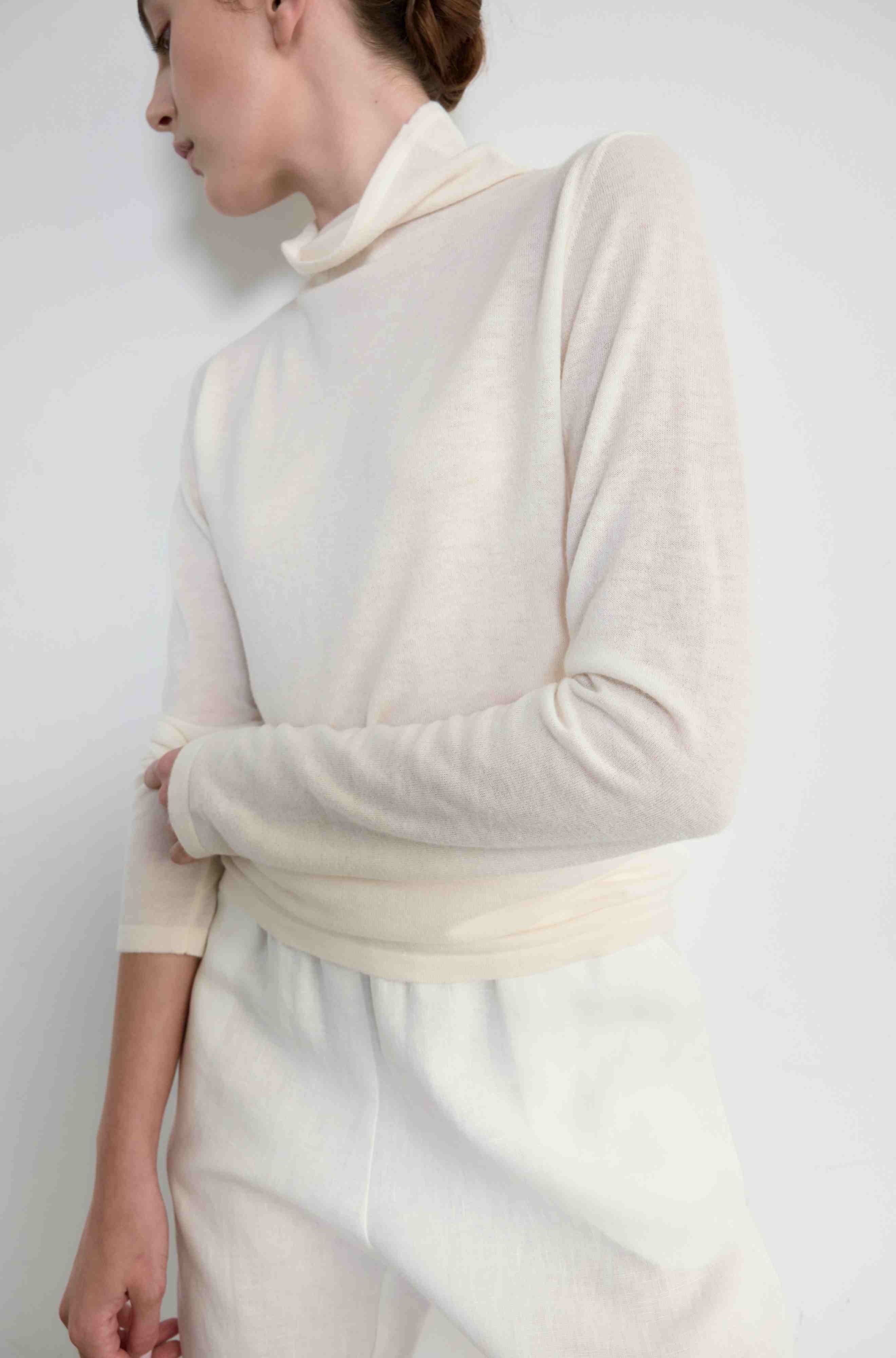 Woman wearing a cream-colored sweater against a white background