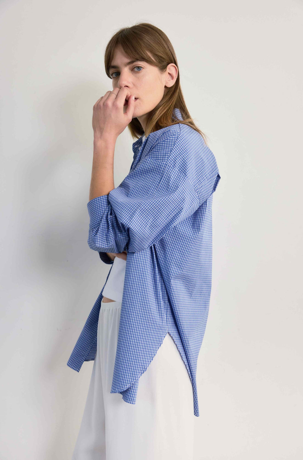 Woman wearing a blue checkered shirt against a plain background