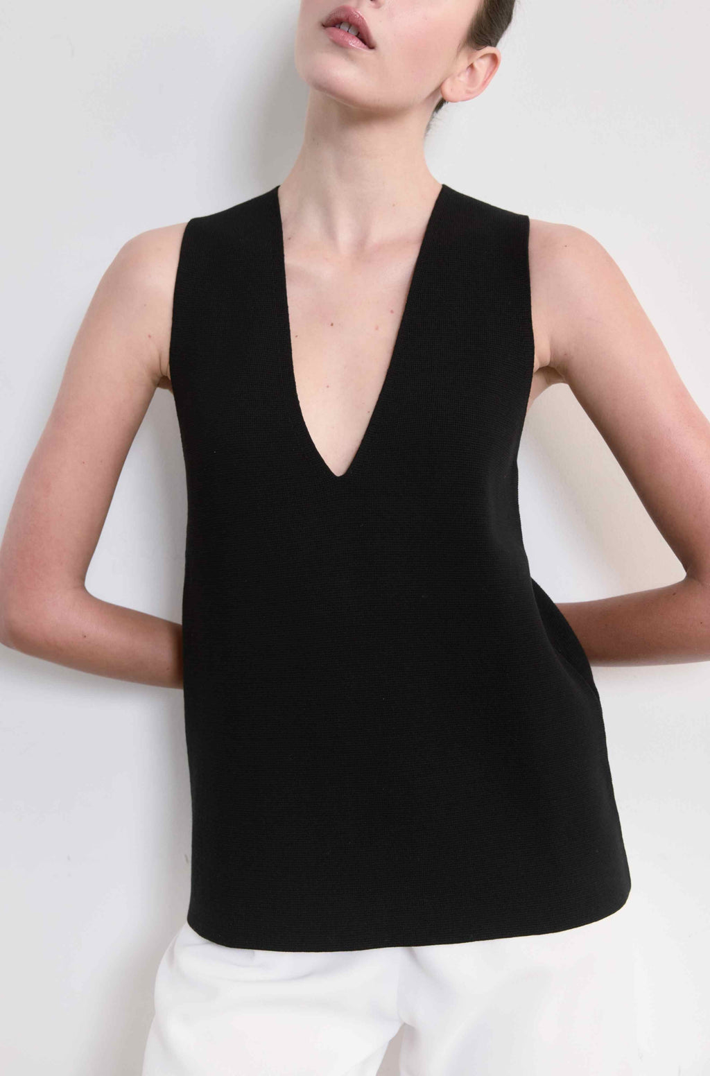 Person wearing a black sleeveless top against a white background