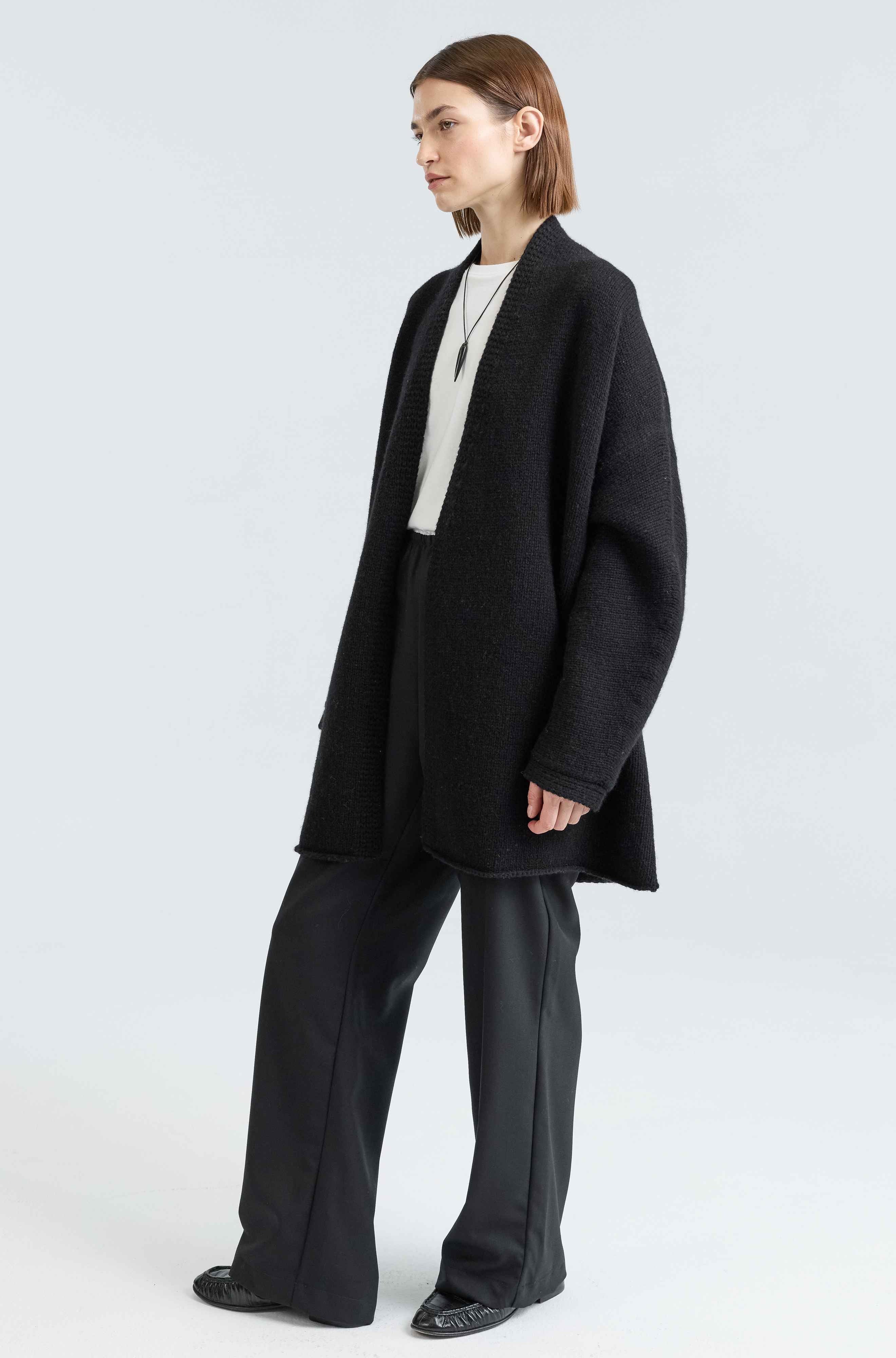 Person wearing a black coat and pants on a white background