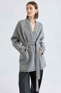 Woman wearing a gray wrap coat on a light gray background