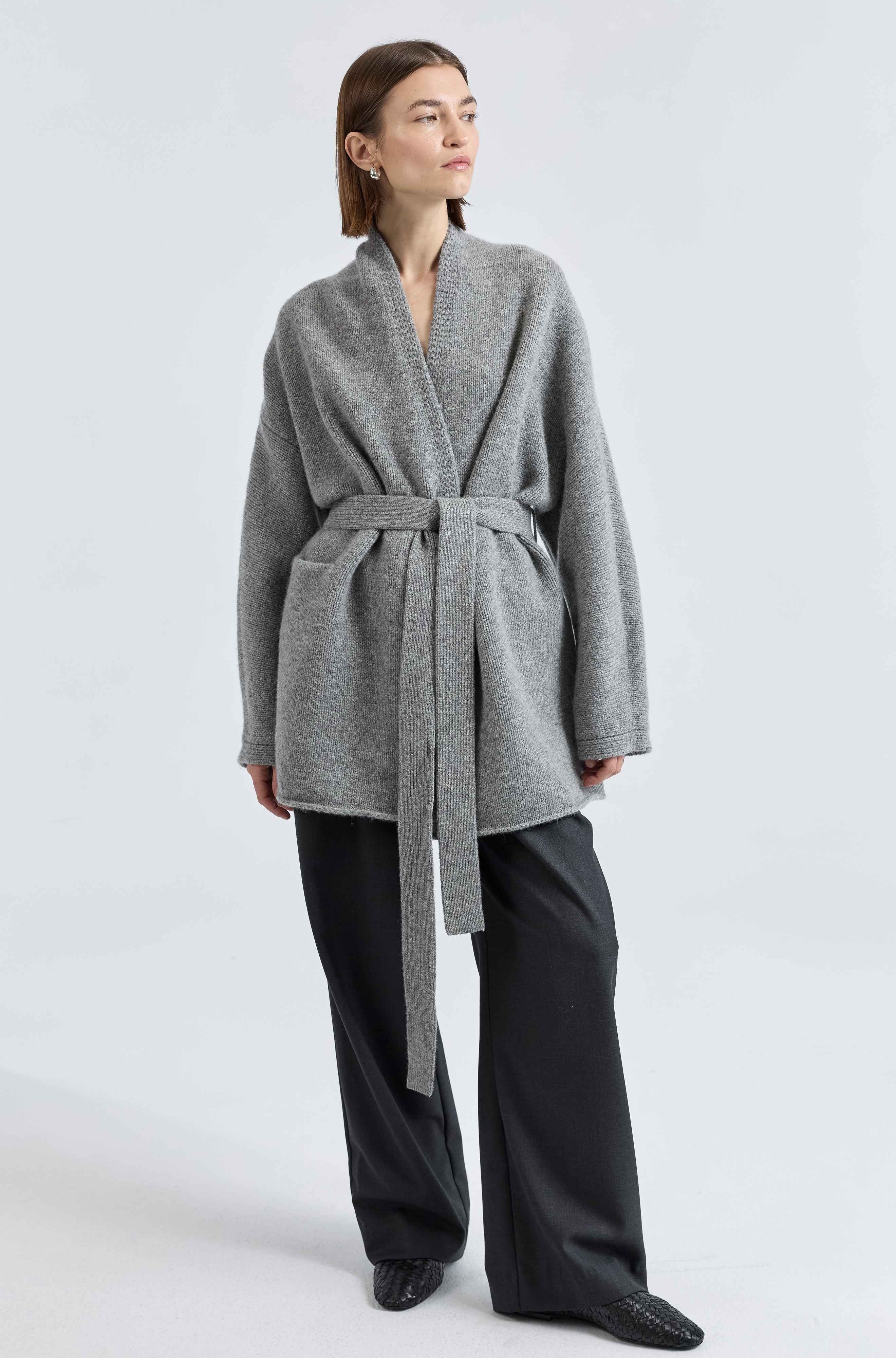 Woman wearing a gray robe over a black outfit on a white background