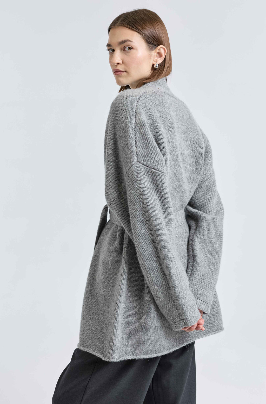 Person wearing a gray cardigan on a light gray background