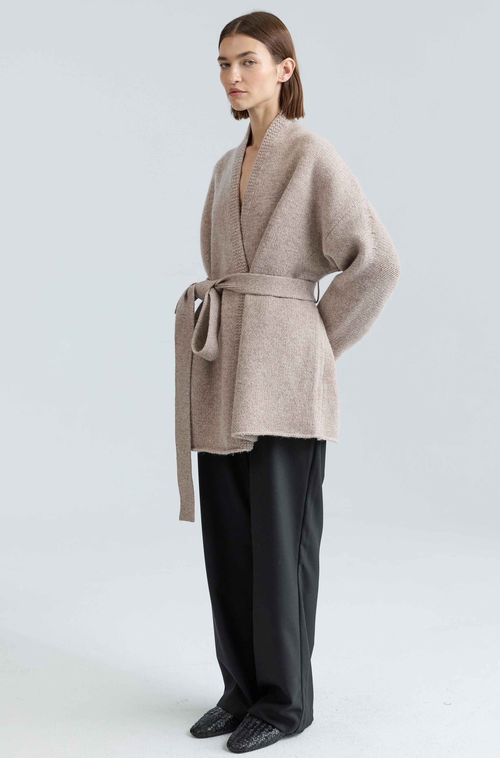 Woman wearing a beige robe-like garment on a white background