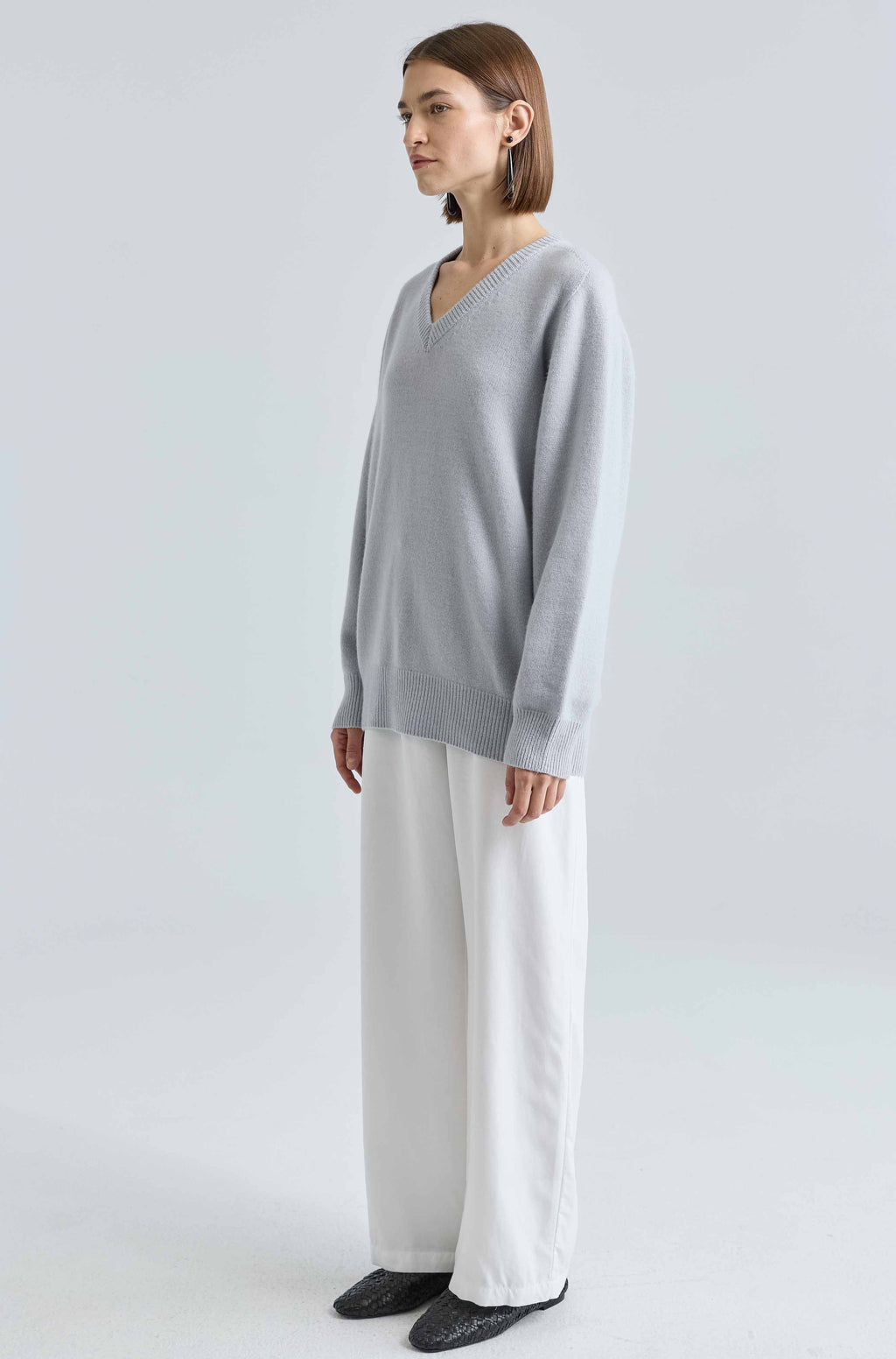 Person wearing a light blue sweater and white pants on a light background