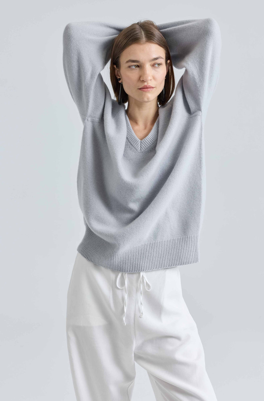 Person wearing a light blue sweater with a hood against a plain background