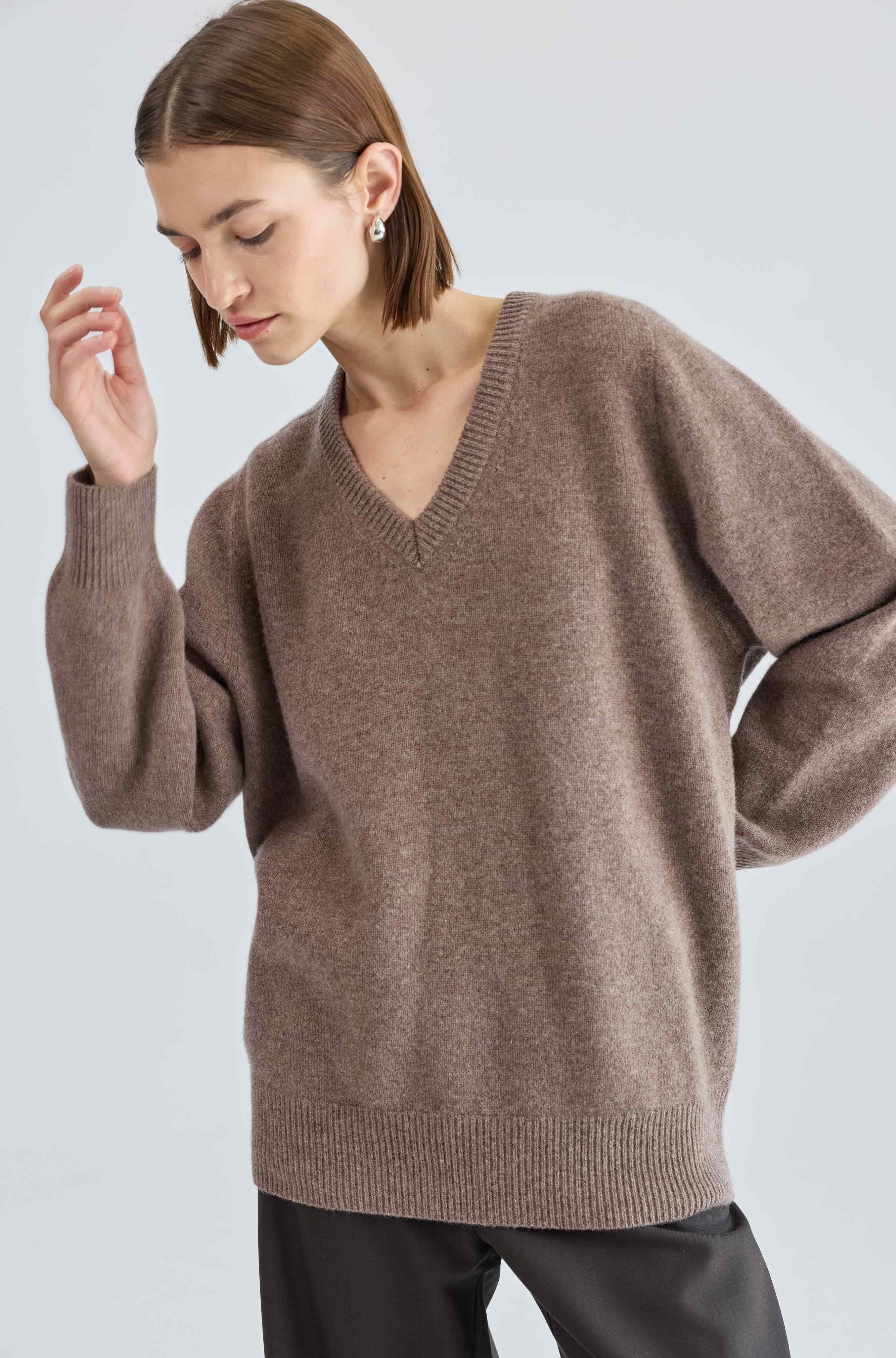 Woman wearing a brown sweater against a white background