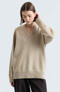 Woman wearing a beige sweater against a light gray background