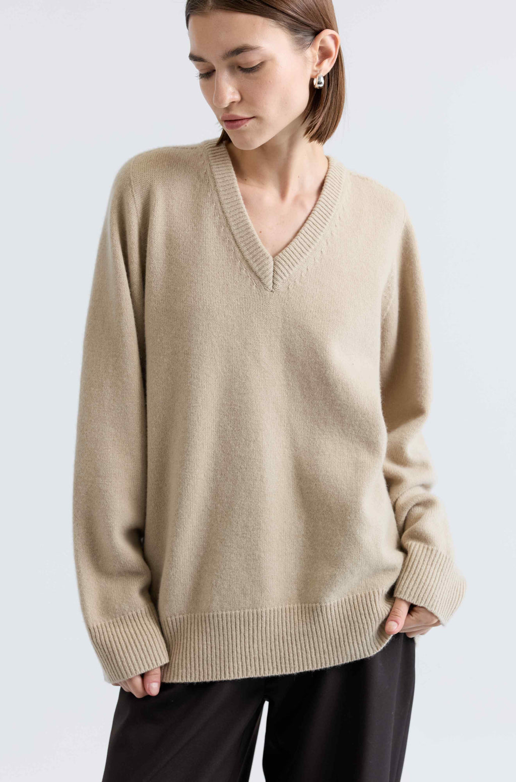 Woman wearing a beige sweater against a light background