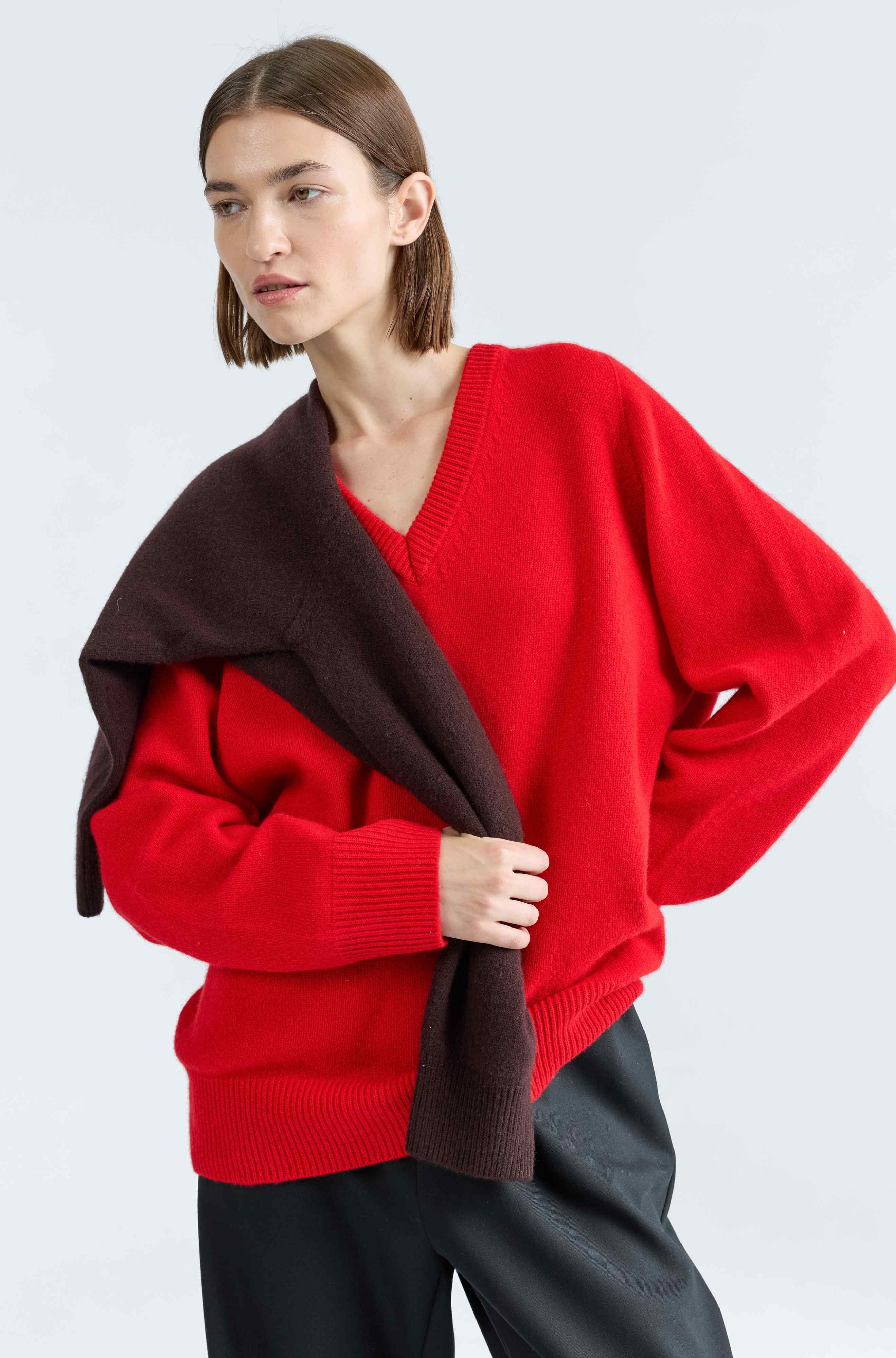 Woman wearing a red sweater with a brown collar against a white background