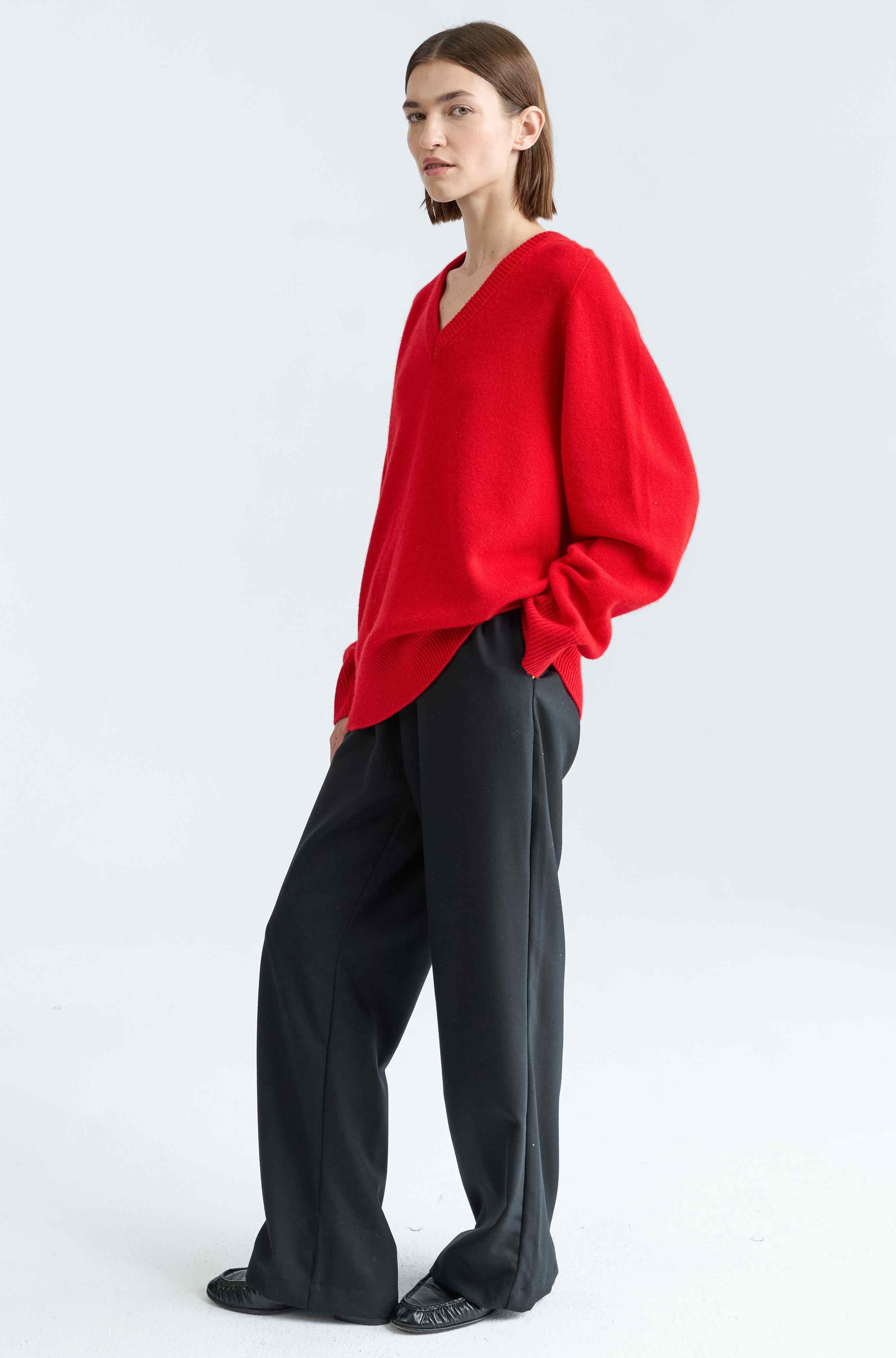 Person wearing a red top and black pants on a white background