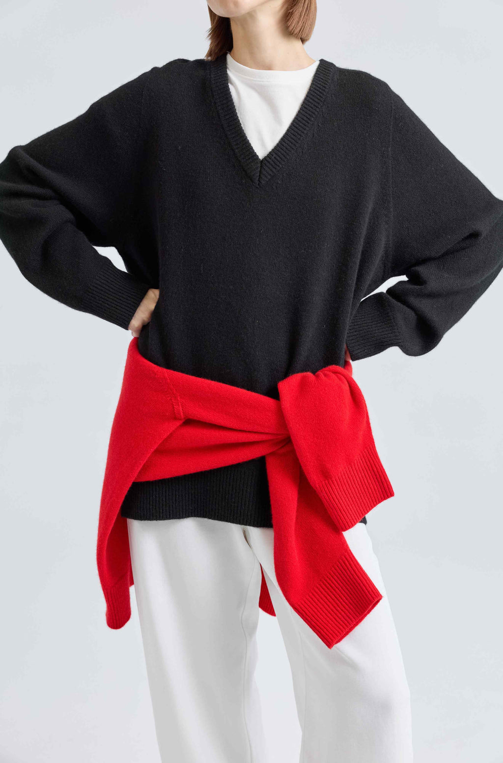 Woman wearing a black wool v-neck sweater with a white tee underneath